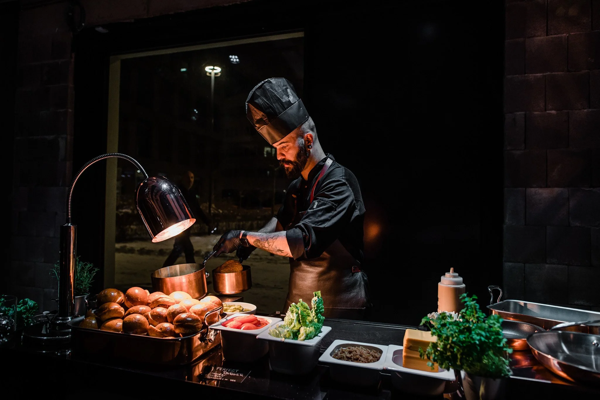 Chef preparing food in a restaurant kitchen at night, surrounded by ingredients and utensils. Catering, culinary and food photography in Zürich, Zug, Bern, Lucerne, Basel, St. Gallen and across Switzerland.