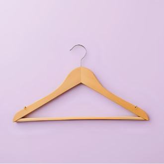 A wooden clothes hanger hanging on a light purple wall.