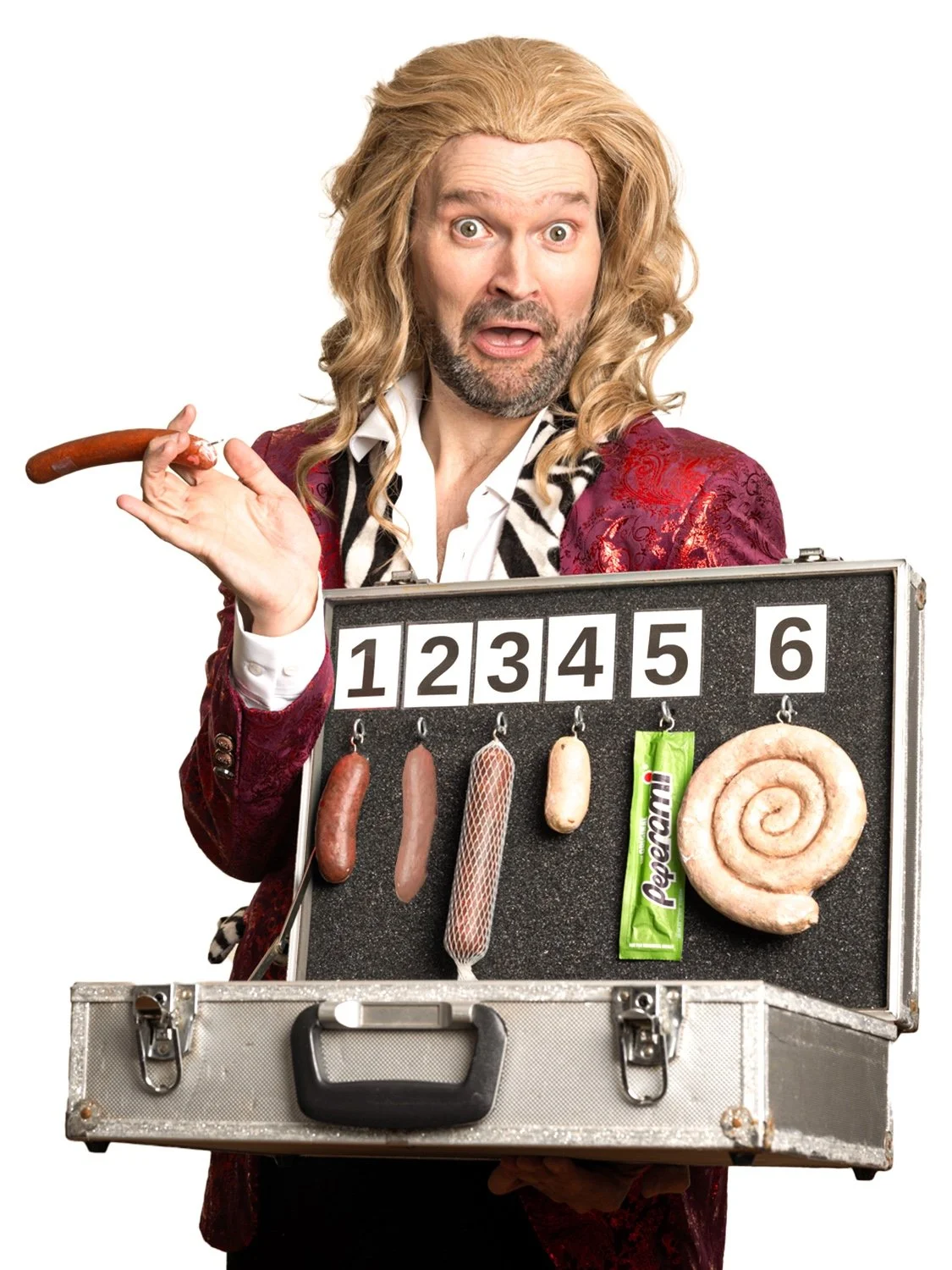 A man with long blonde hair, dressed in a red patterned jacket and white shirt, holding a case with sausages and snacks, and gesturing with a surprised expression.