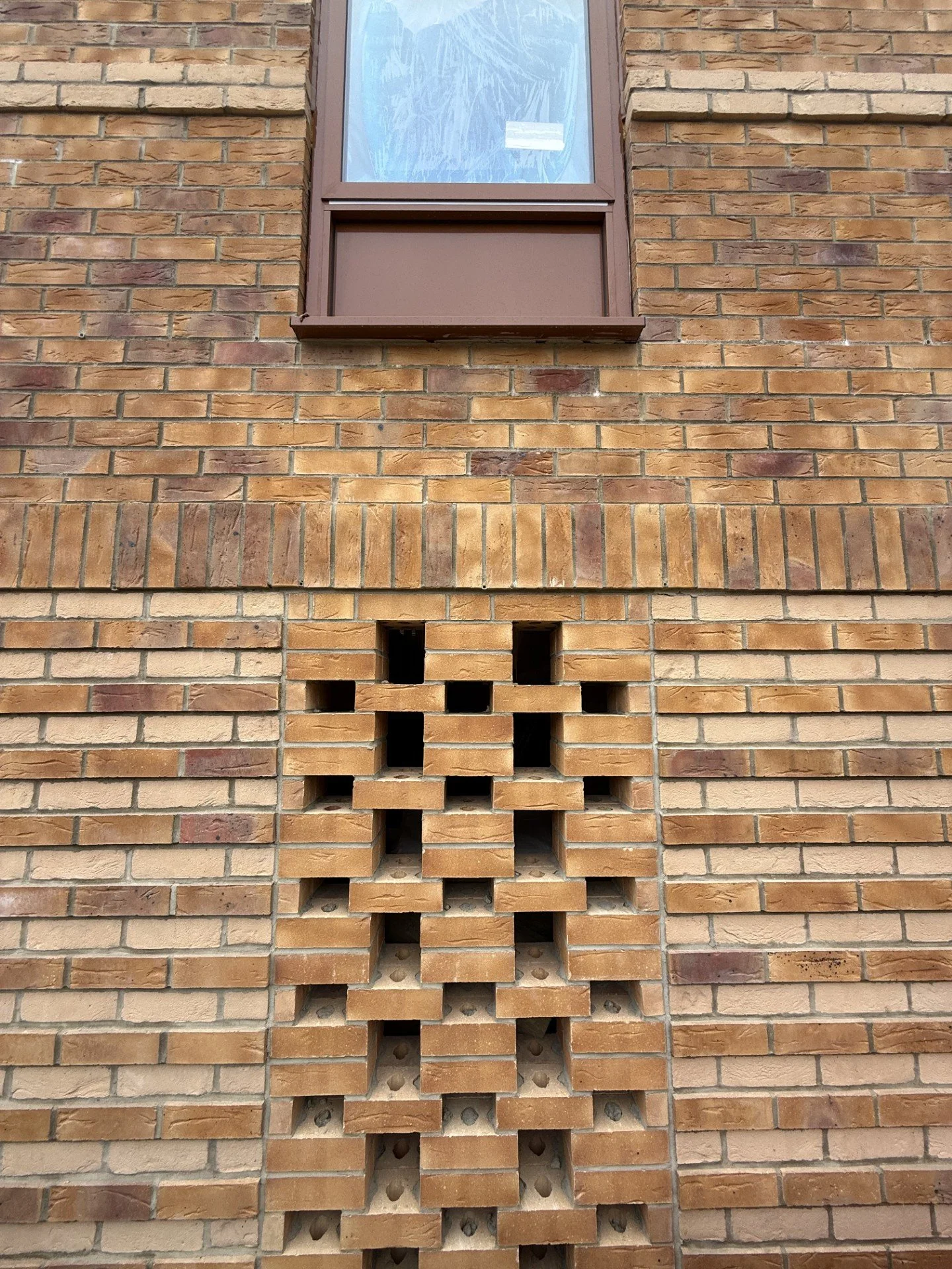 Brick wall with a small window above and a decorative brick pattern below.