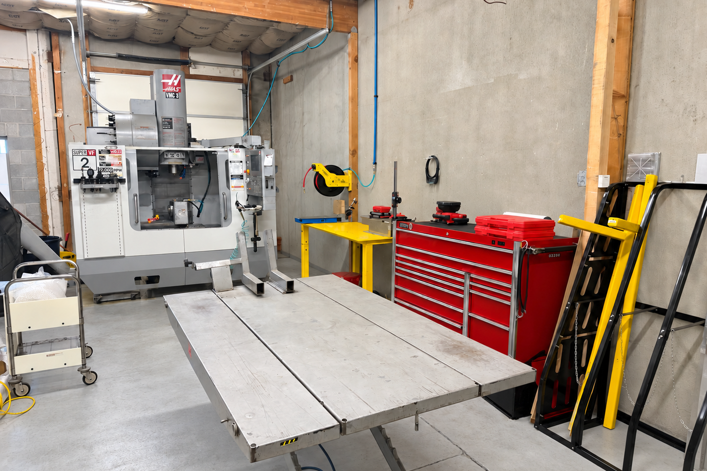 Inside the Ricks Machining shop, with a worktable, tools, and the Odin CNC mill.