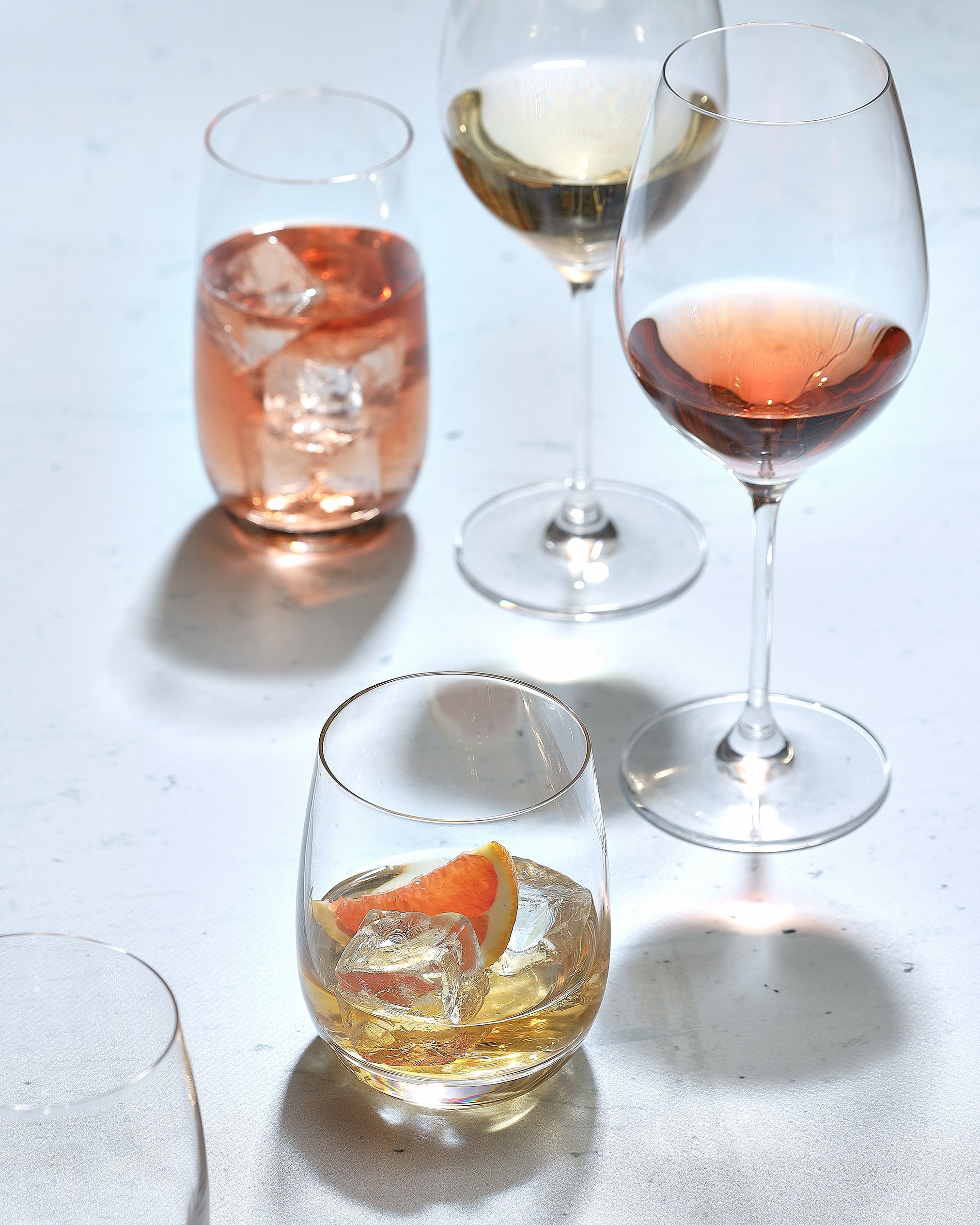 Sarah Ghijselinck, food and drink stylist, art direction, recipe development, Gent, fine dining, restaurant photography, tableware photography, Various glasses of wine and a cocktail on a white surface.