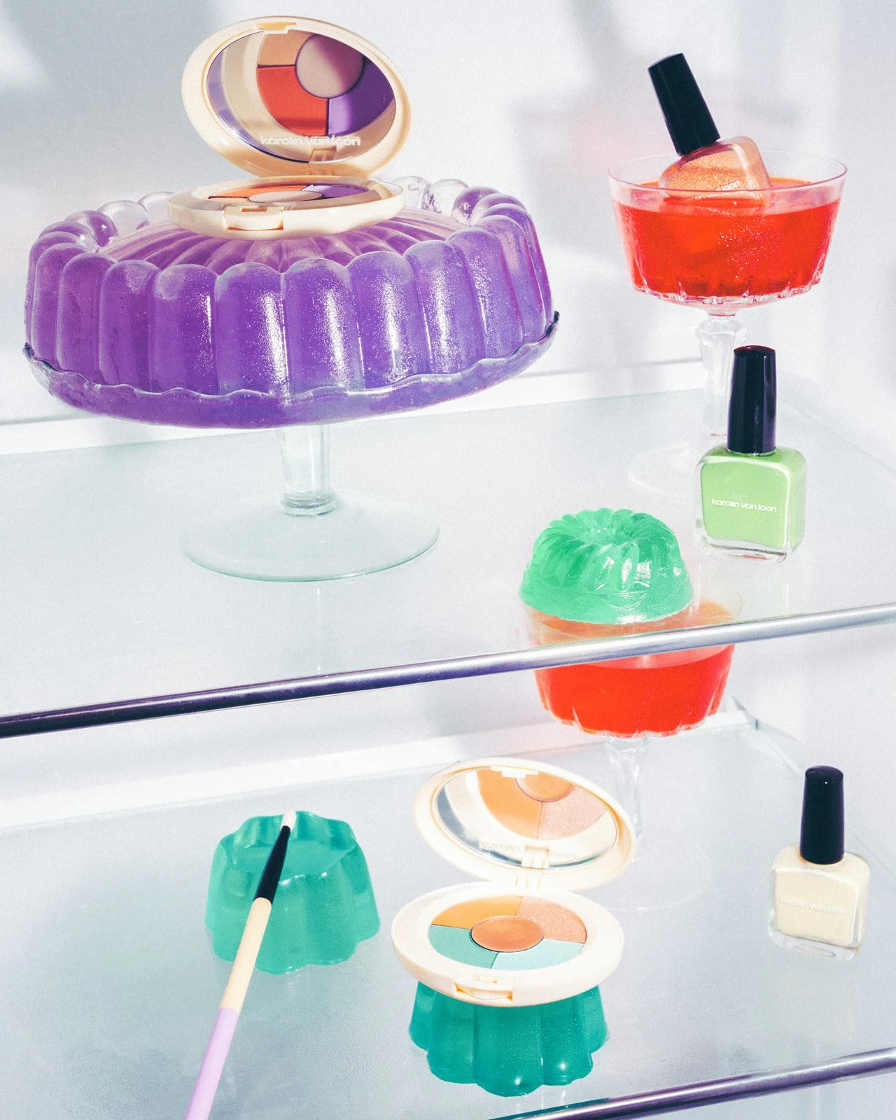 Jello food styling, art direction, Liz Dvorkina, fridge full of colorful makeup items including an eyeshadow palette, nail polish bottles, makeup brushes, and gel-like containers on mirrored shelves.