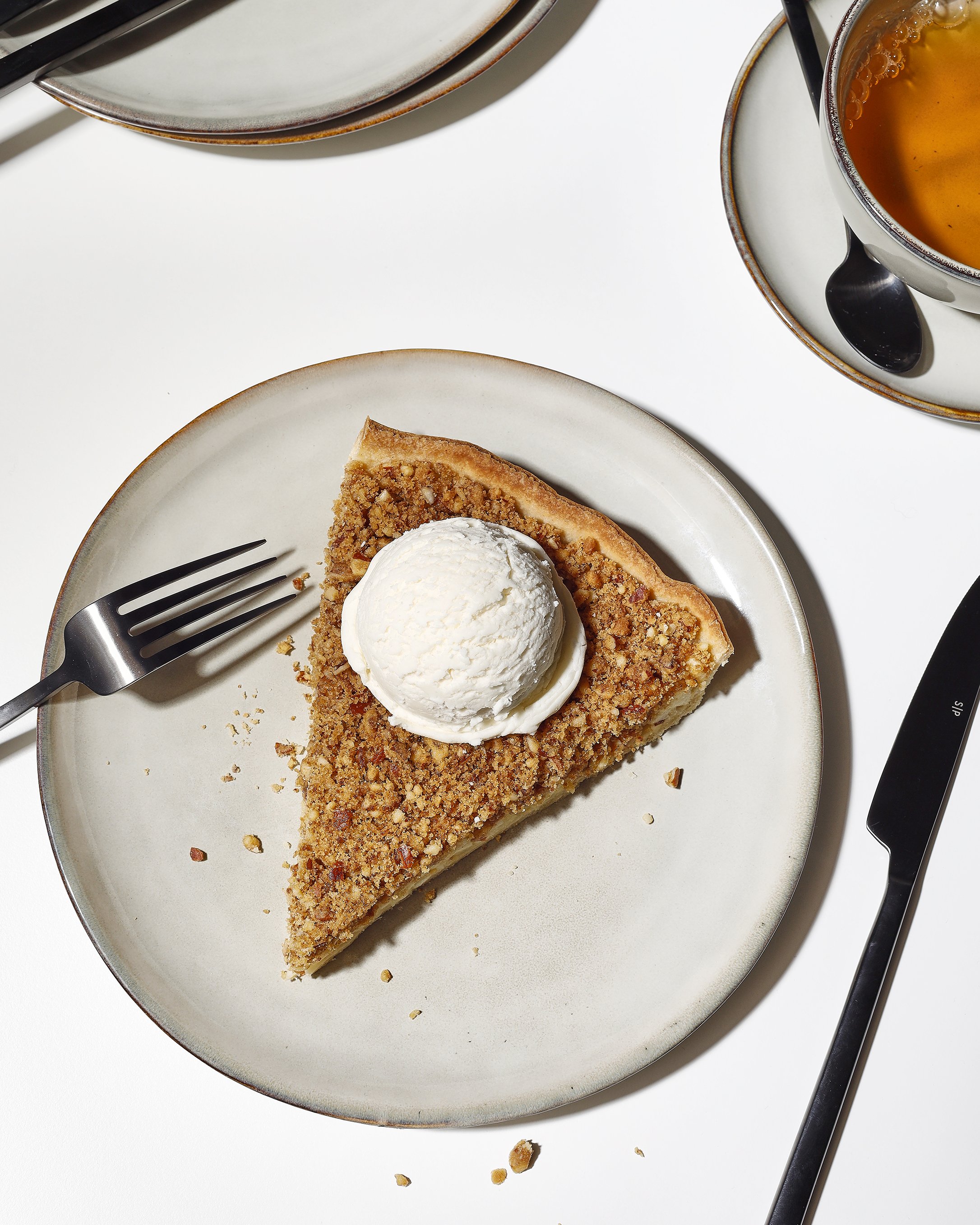 Sarah Ghijselinck food stylist, A slice of pie with a crumb topping and a scoop of vanilla ice cream on top, served on a beige Salt & Pepper plate. 