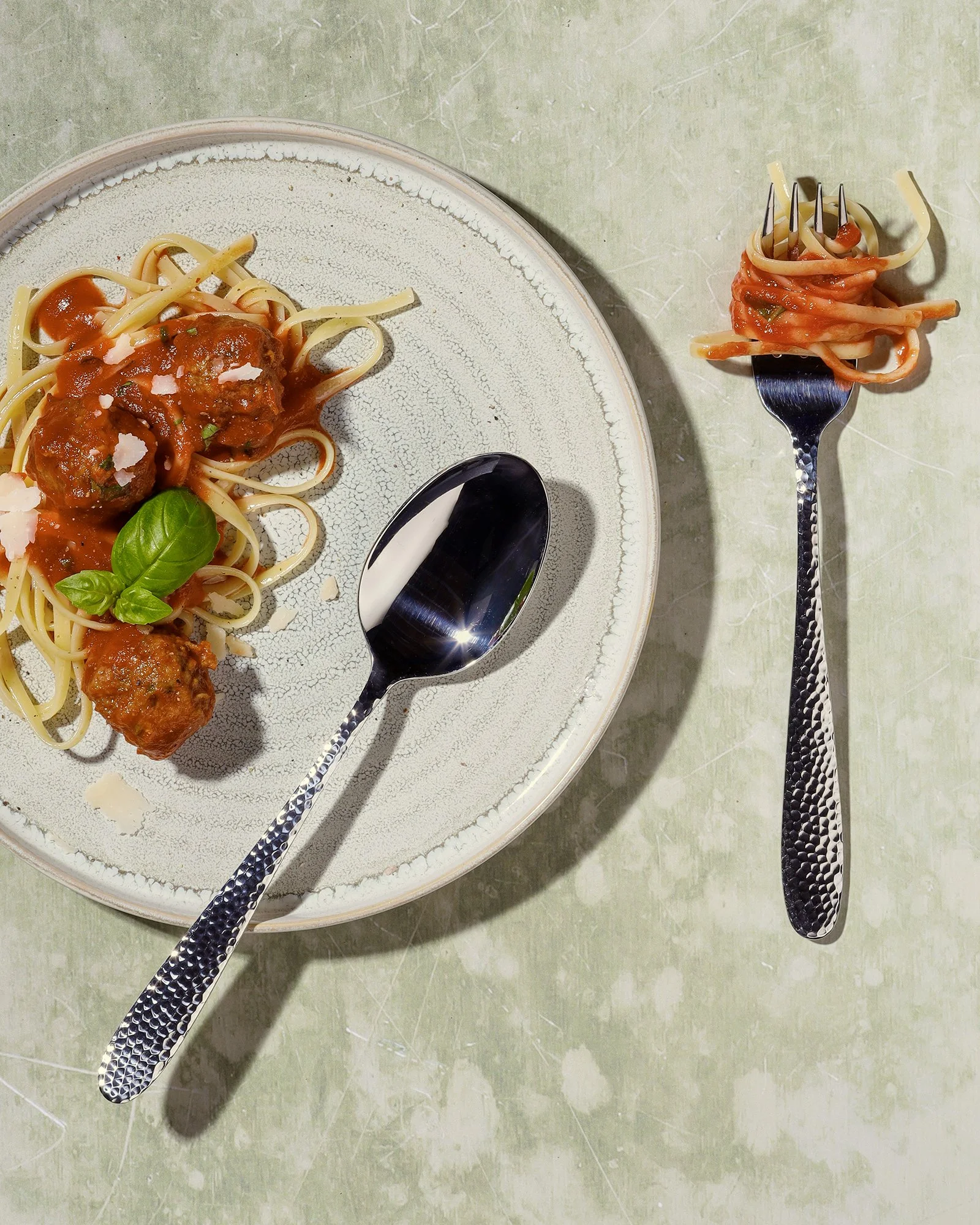 Sarah Ghijselinck, food and drink stylist, art direction, recipe development, Gent, fine dining, restaurant photography, tableware photography, Plate of spaghetti with meatballs,. A fork with spaghetti on it is positioned beside the plate.
