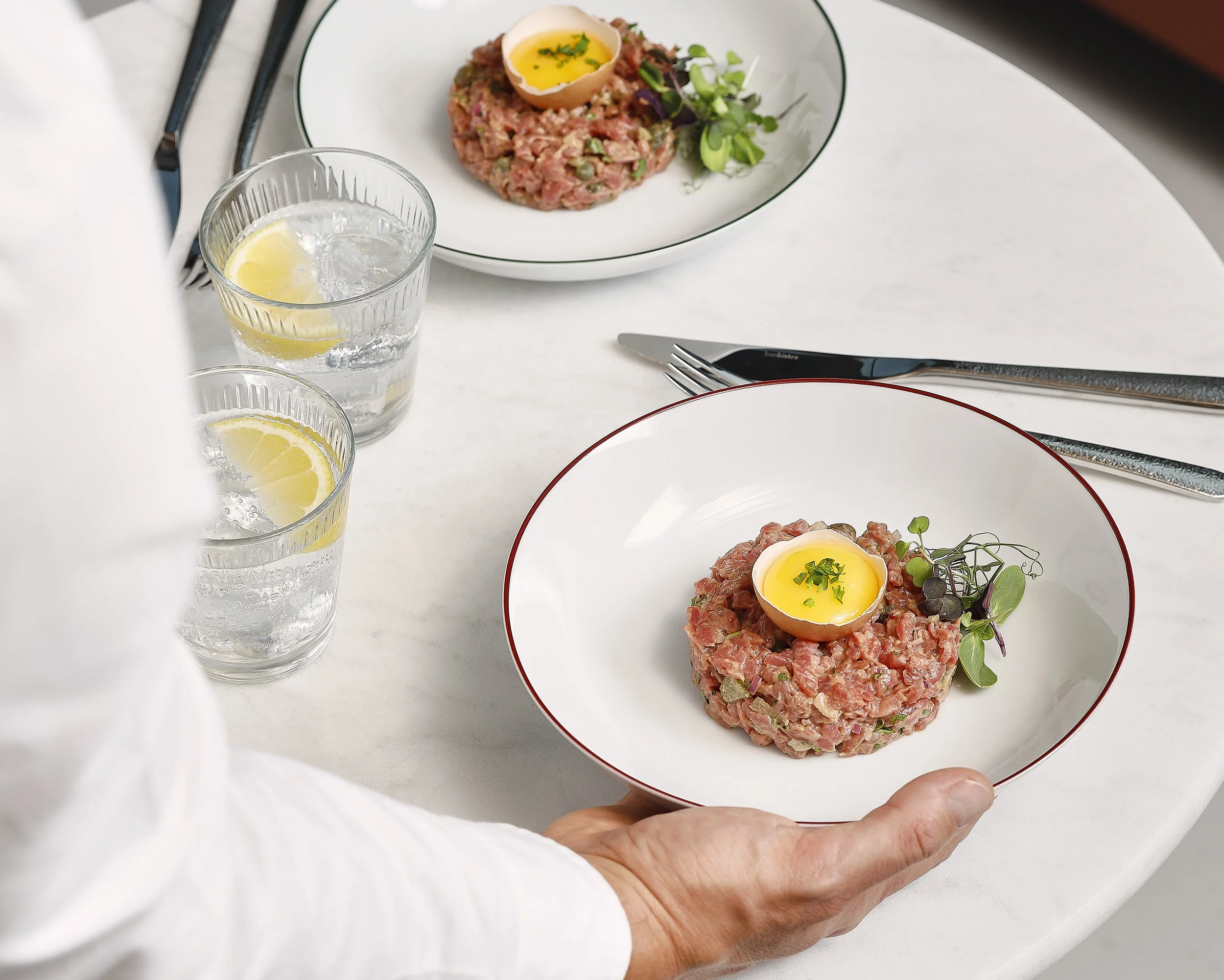 Sarah Ghijselinck food stylist, restaurant fine dining, A plate with tartare topped with a soft-boiled egg half and garnished with herbs