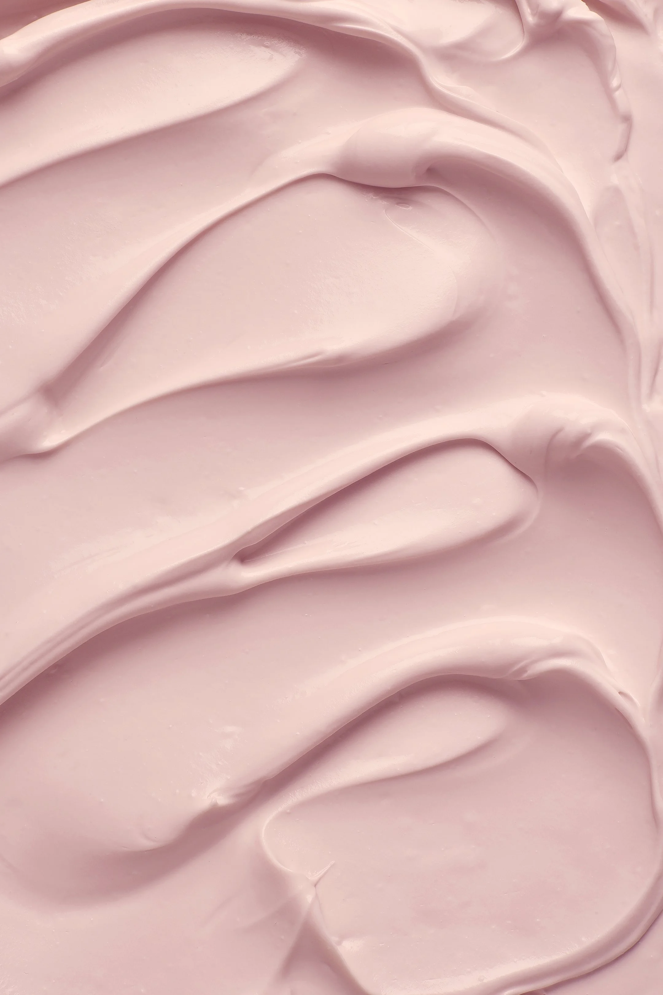 Food styling Gent. Close-up of light pink, smooth, and creamy textured ice cream, likely a cosmetic product or frosting.