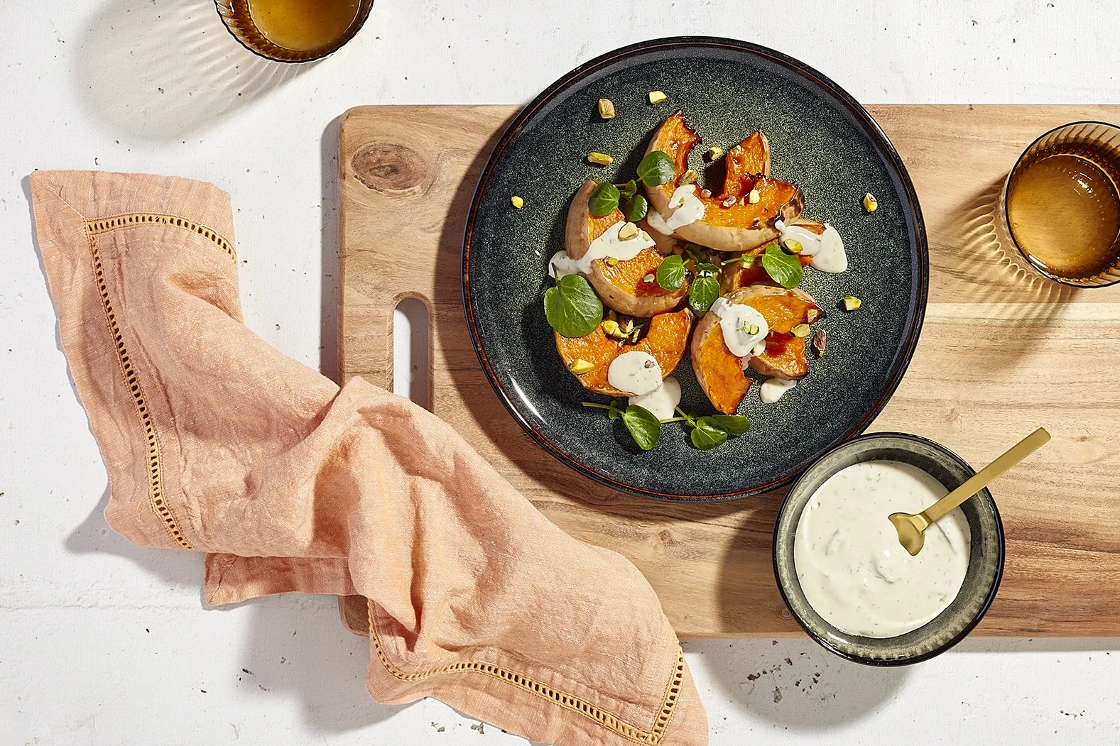 Sarah Ghijselinck, food and drink stylist, art direction, recipe development, Gent, fine dining, restaurant photography, tableware photography, Sliced roasted pumpkins garnished with green herbs, drizzled with white creamy sauce
