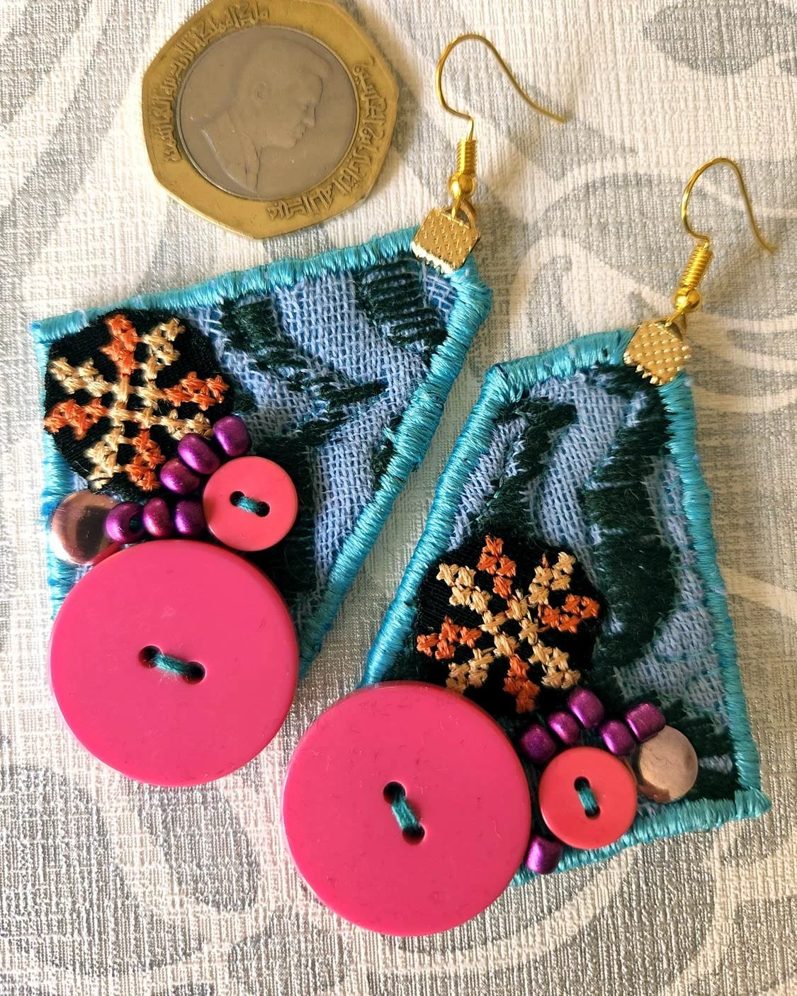 What makes this free form earring special is the Keffiyeh pattern in the background with beads, buttons and Palestinian embroidery , made in Jordan