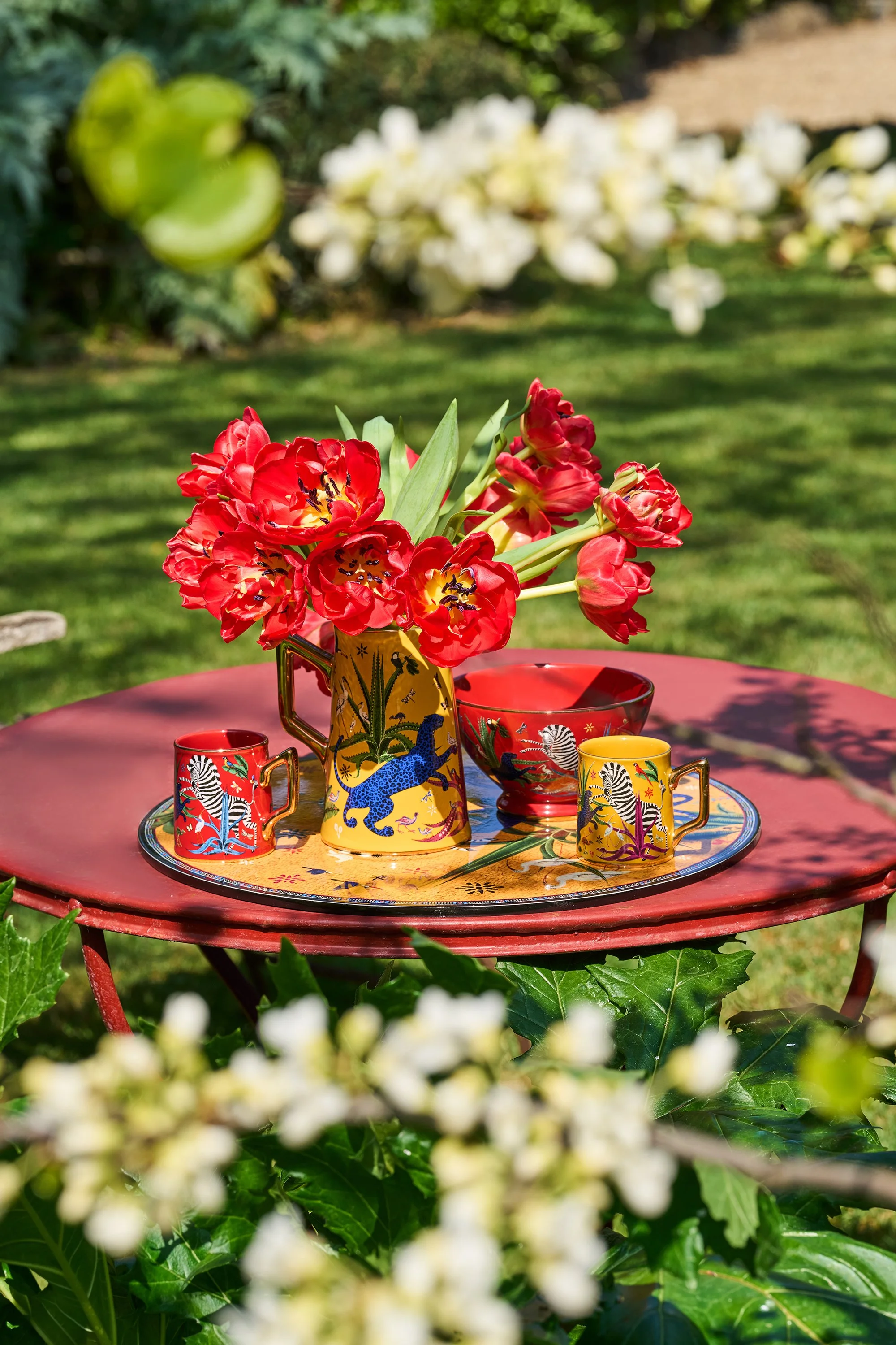 Scatto lifestyle di un servito Ortigia Sicilia in giardino con bouquet di tulipani rossi.
