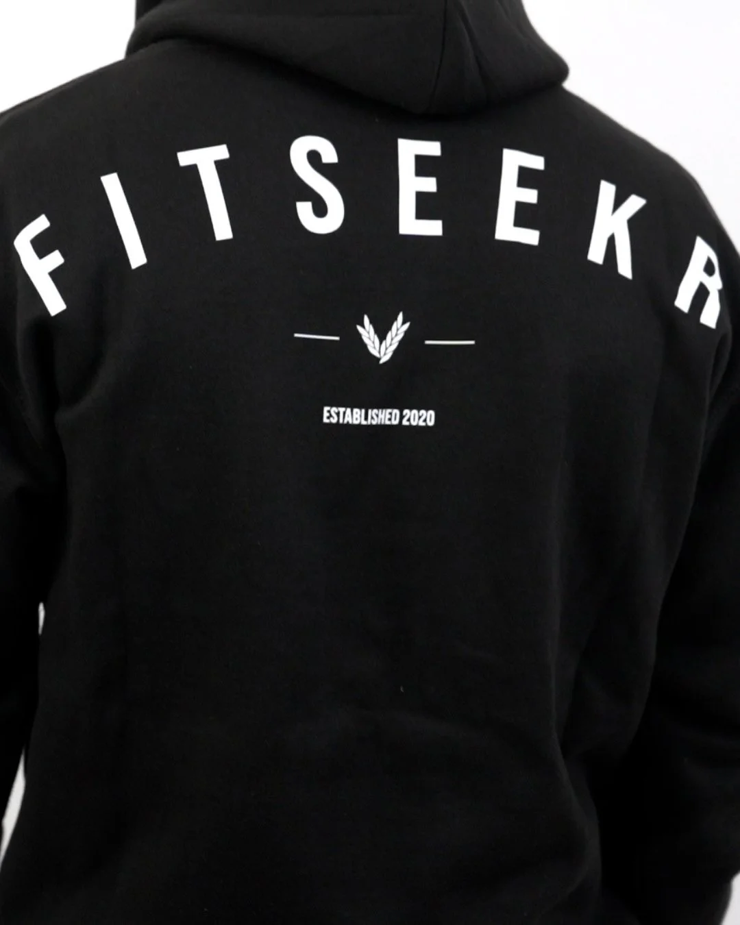 Back of person wearing black hoodie with white text reading 'FITS EEK' and a small graphic and text below that says 'ESTABLISHED 2020'.