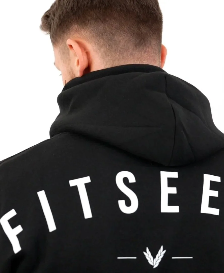Back of a man wearing a black hoodie with white text that reads 'FITS' and a small graphic of leaves underneath.