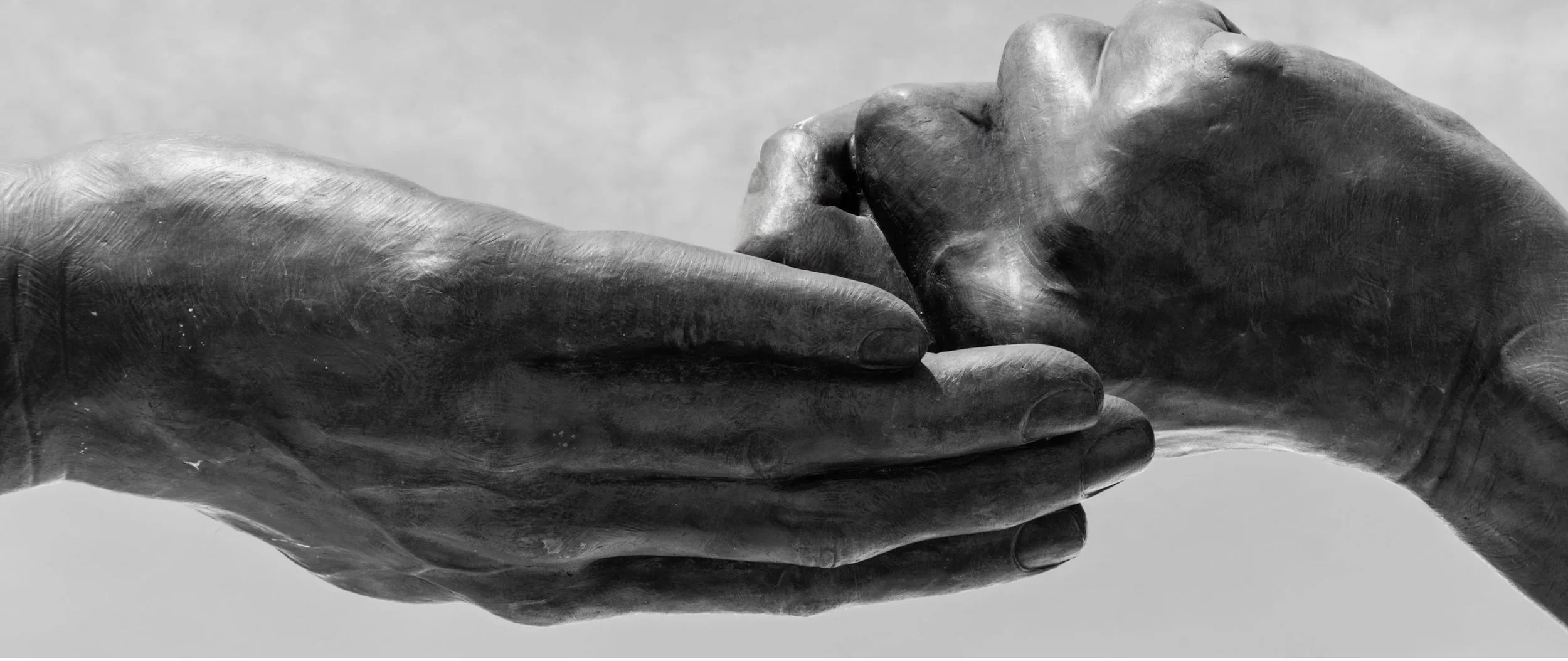 Two sculpted hands - one open, the other half closed resting on it.