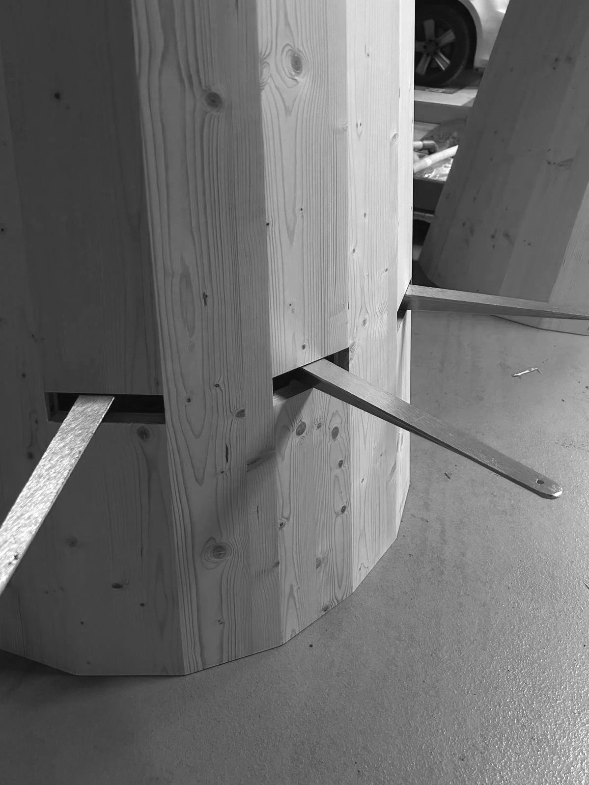 A custom wooden structure under construction, featuring assembled timber components and metal supports for stability during the fabrication process.