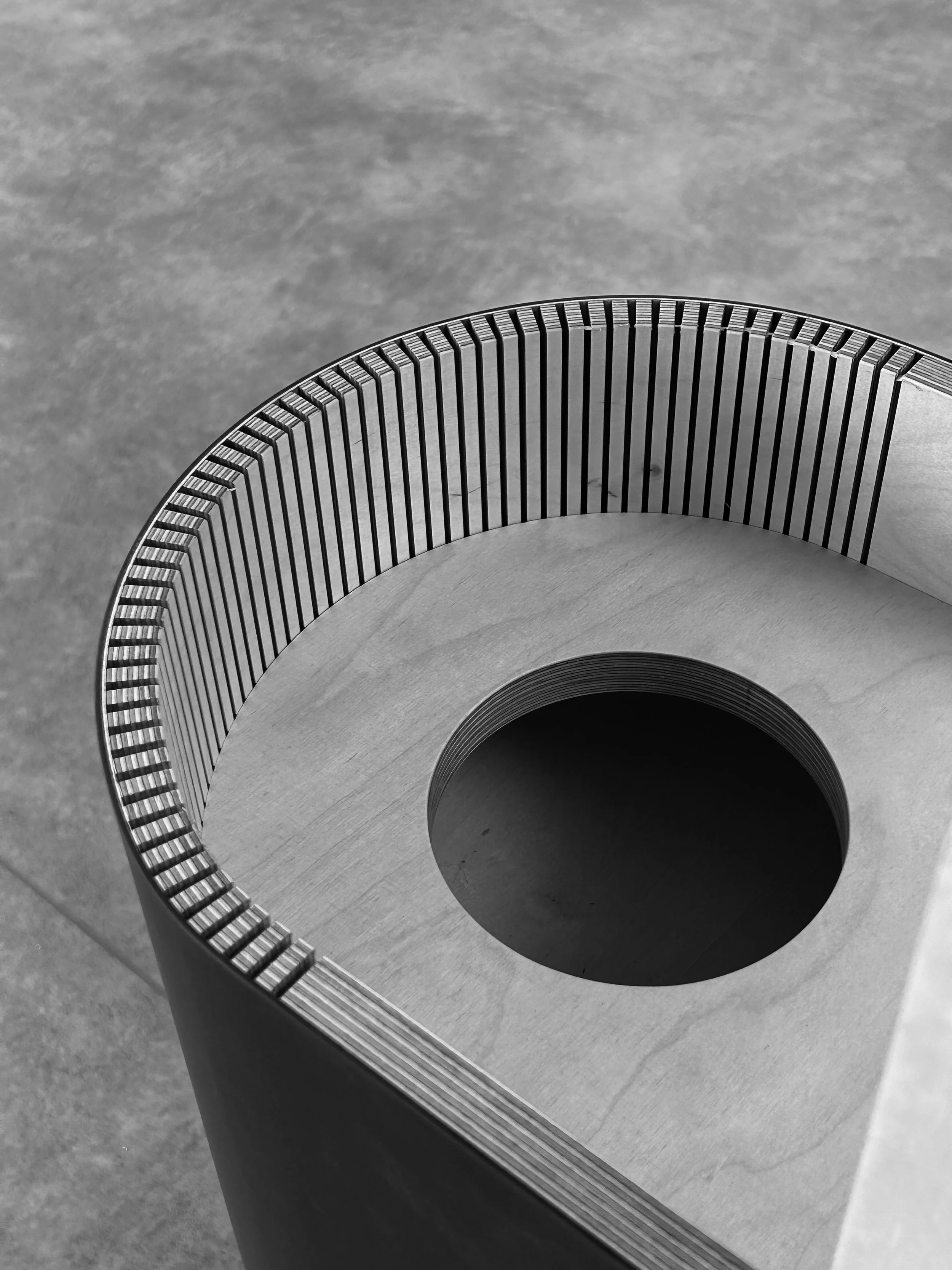 Custom flower stand crafted from bent wood and linoleum, combining sustainable materials with contemporary furniture design.