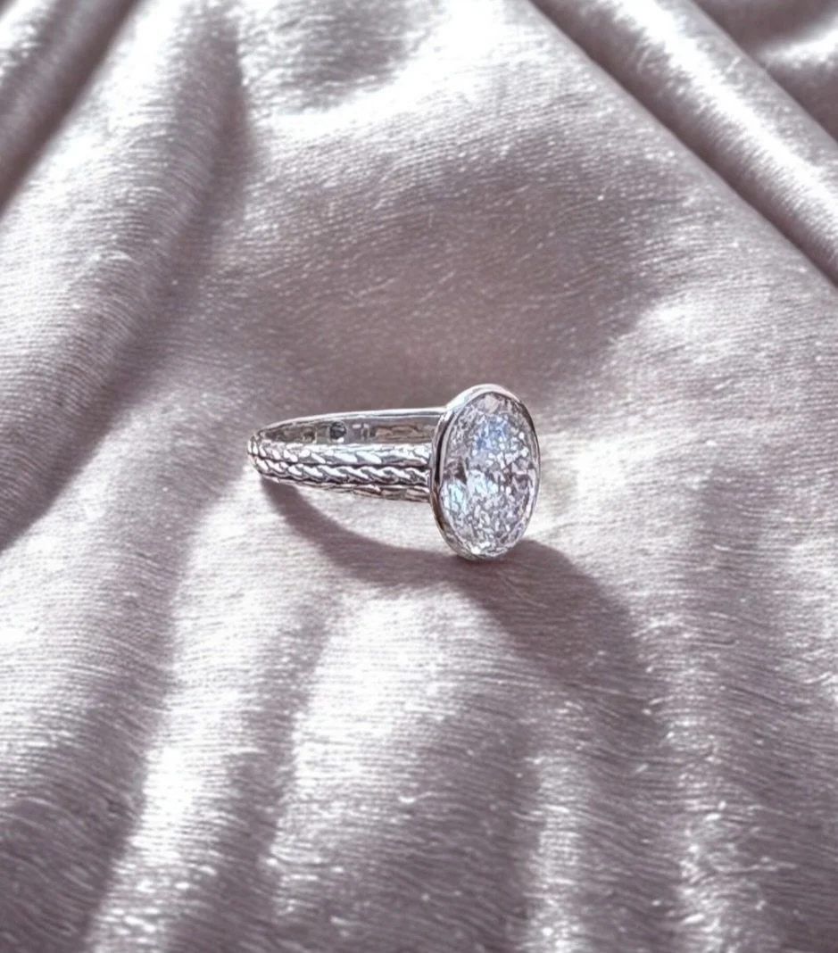 Ancient Zoroastrian Persian flames entwined with a Celtic knot. Topaz and peridot birthstones woven into the design. A union of two cultures

At the centre: a reimagined ethical masterpiece, a 3ct D colour oval, excellent cut diamond.
Cradled by the 