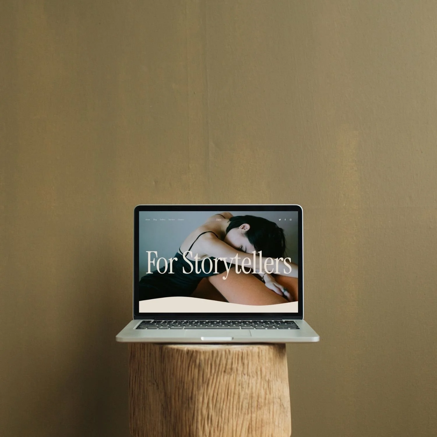 A laptop on a wooden stand displaying a website with a woman resting and the text 'For Storytellers' on the screen.