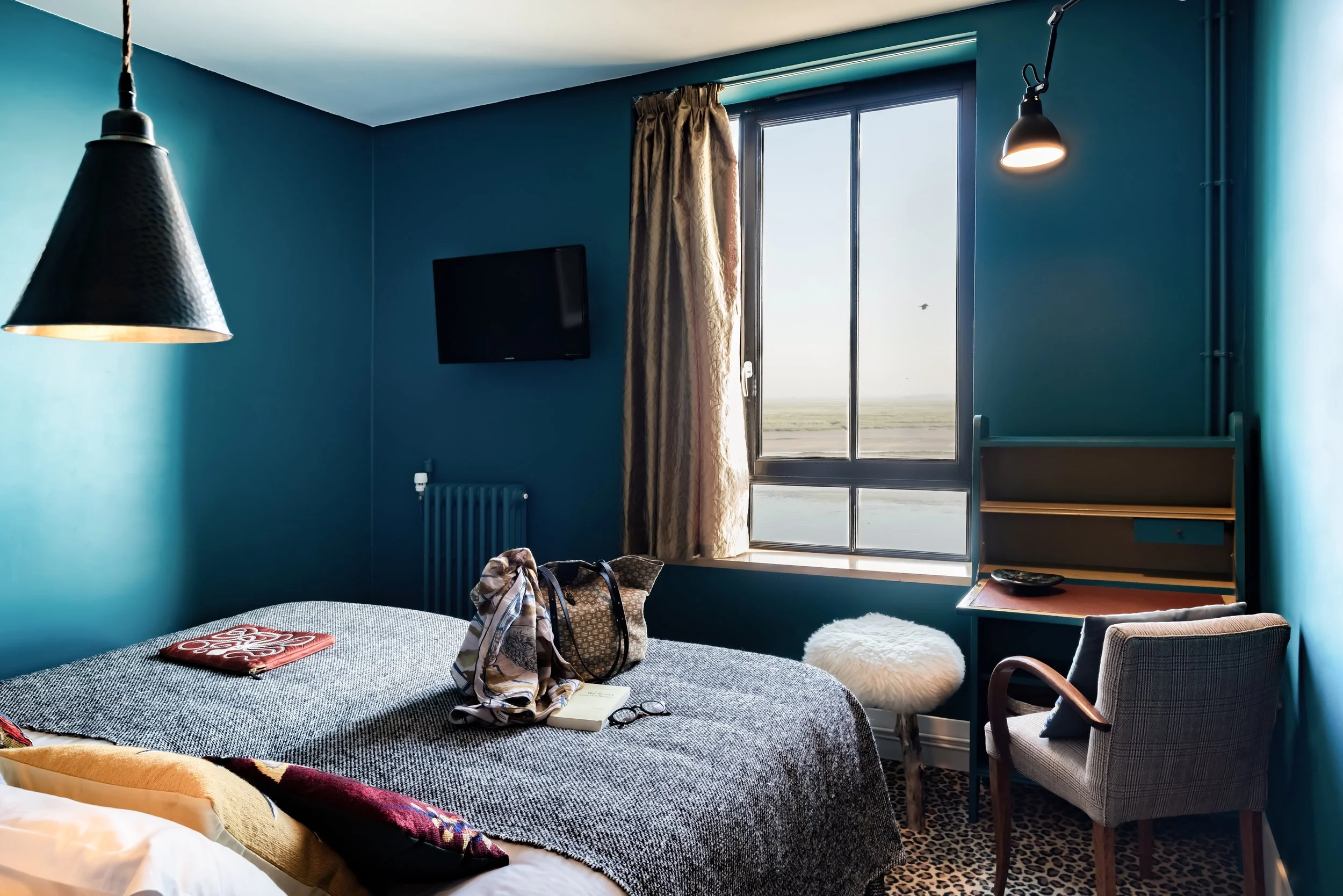 Chambre avec lit, fauteuil, bureau, télévision et vue sur la rivière