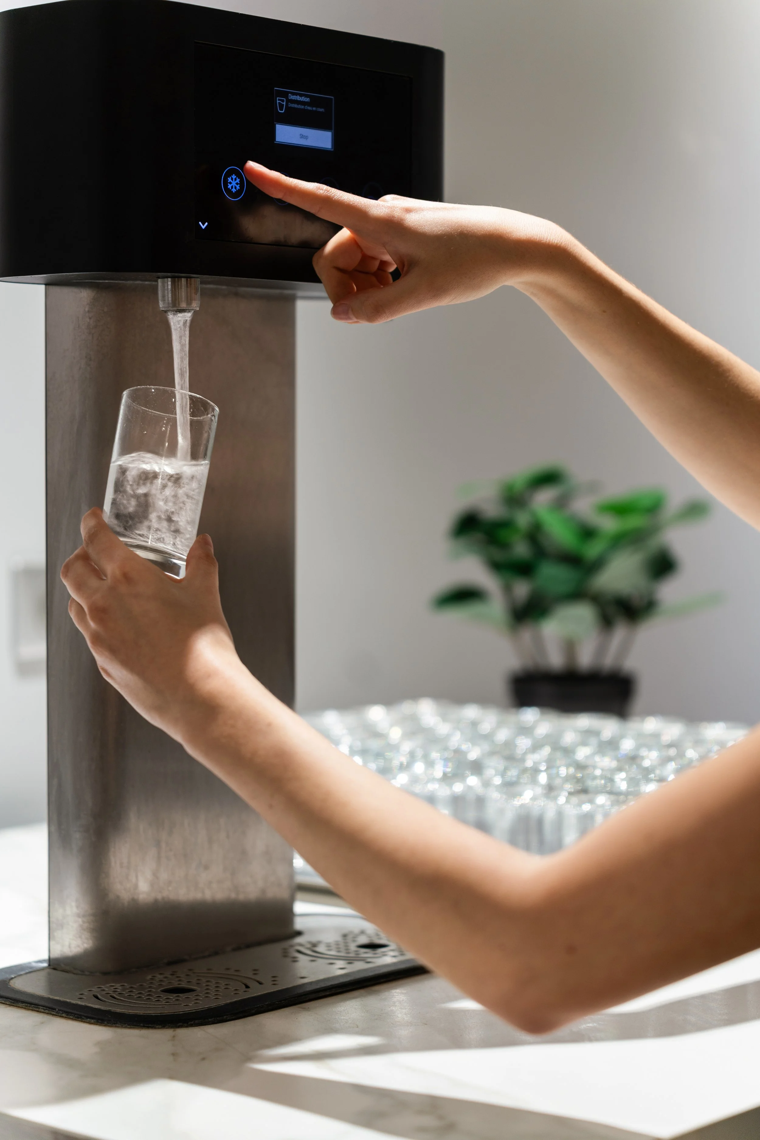 Une personne remplissant un verre d'eau à partir d'une fontaine d'eau moderne.
