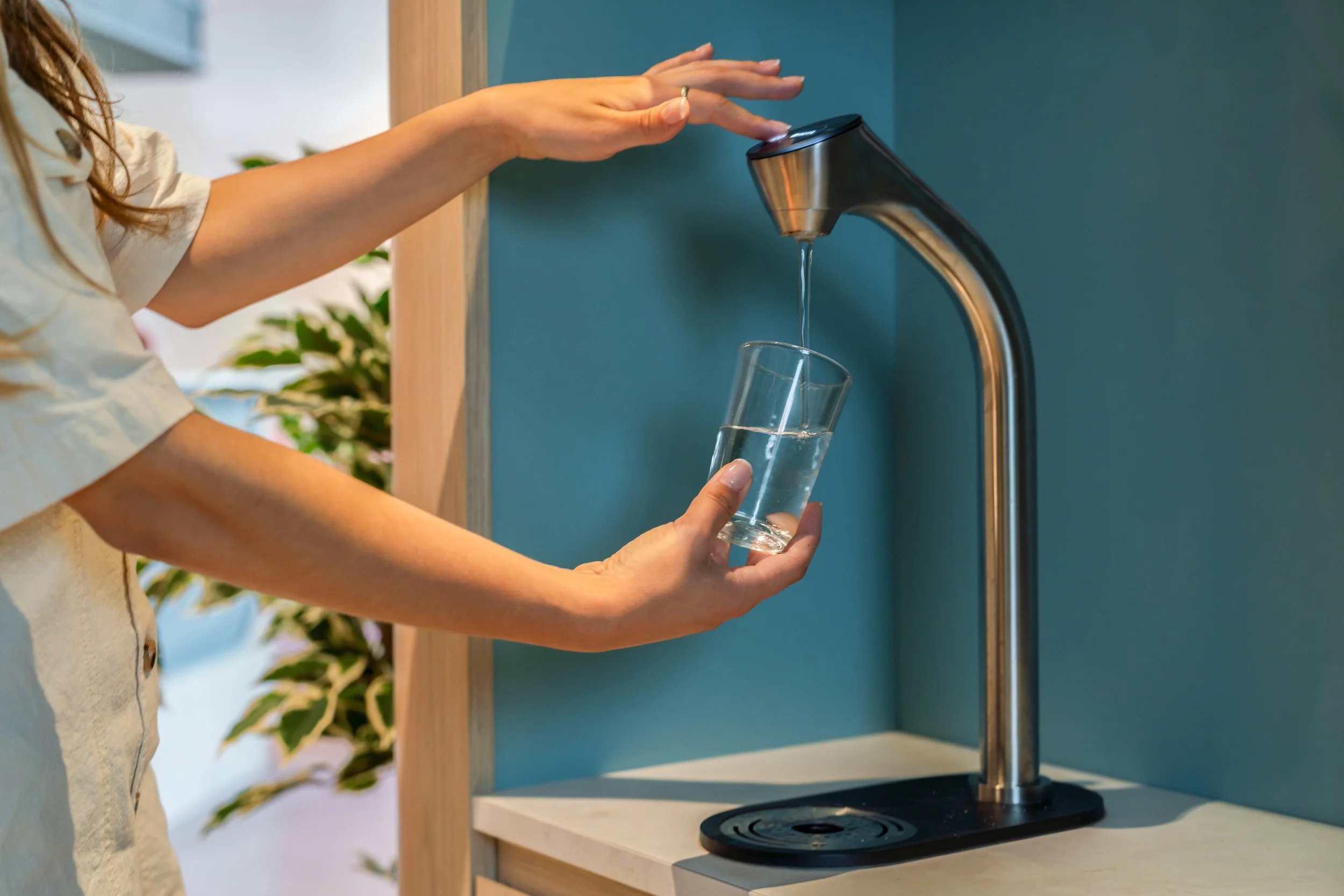Personne remplissant un verre d'eau sous une fontaine.