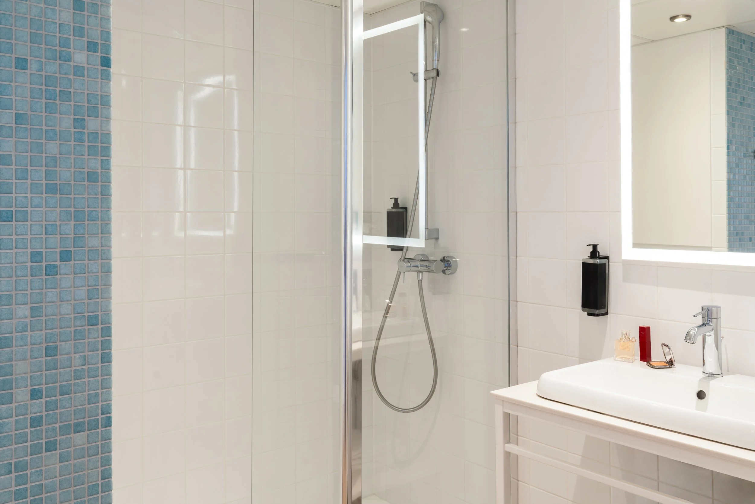 Salle de bain moderne avec douche en verre, vasque blanche et miroir avec éclairage LED