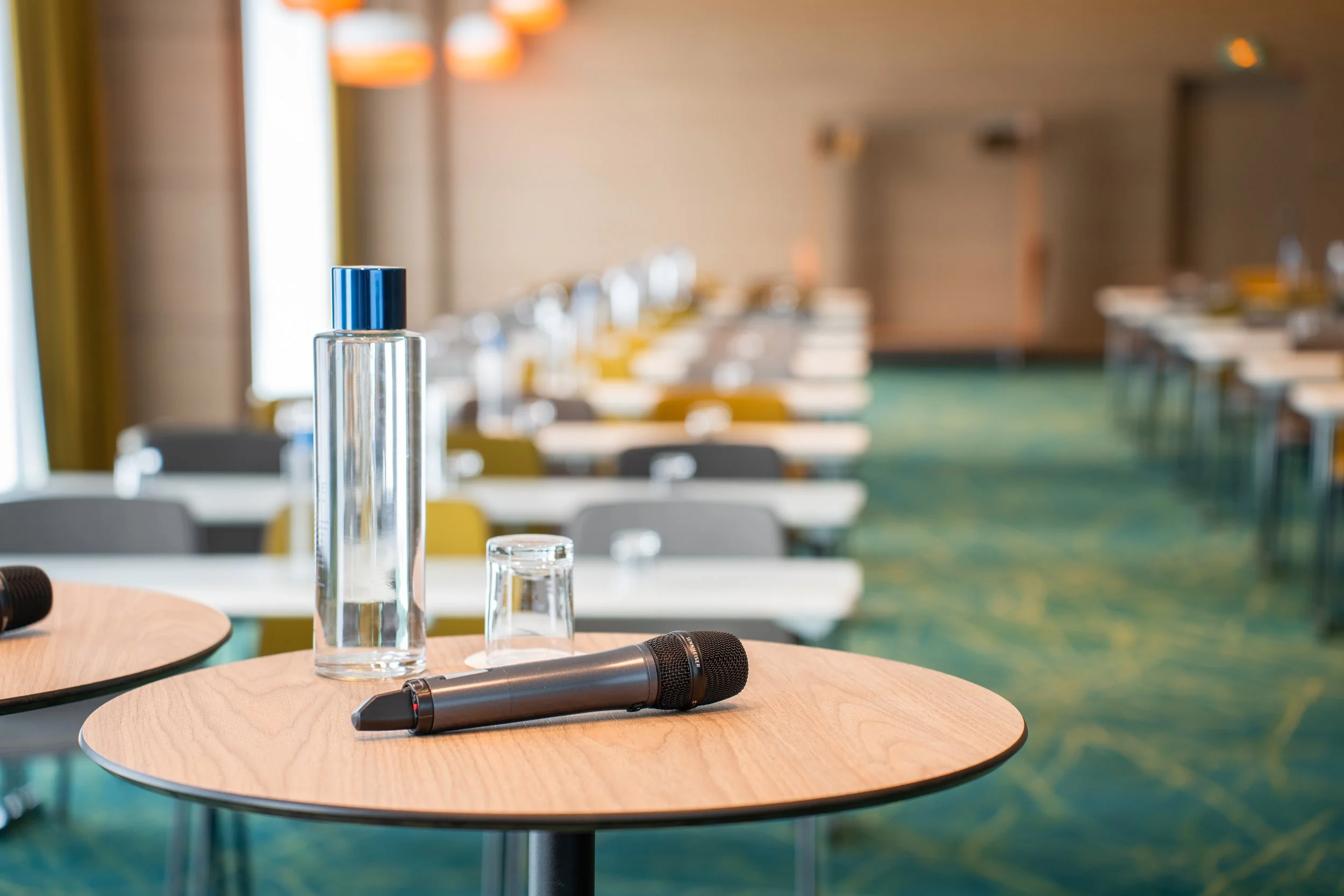 Microphone, bouteille d'eau et verre sur une table dans une salle de conférence vide