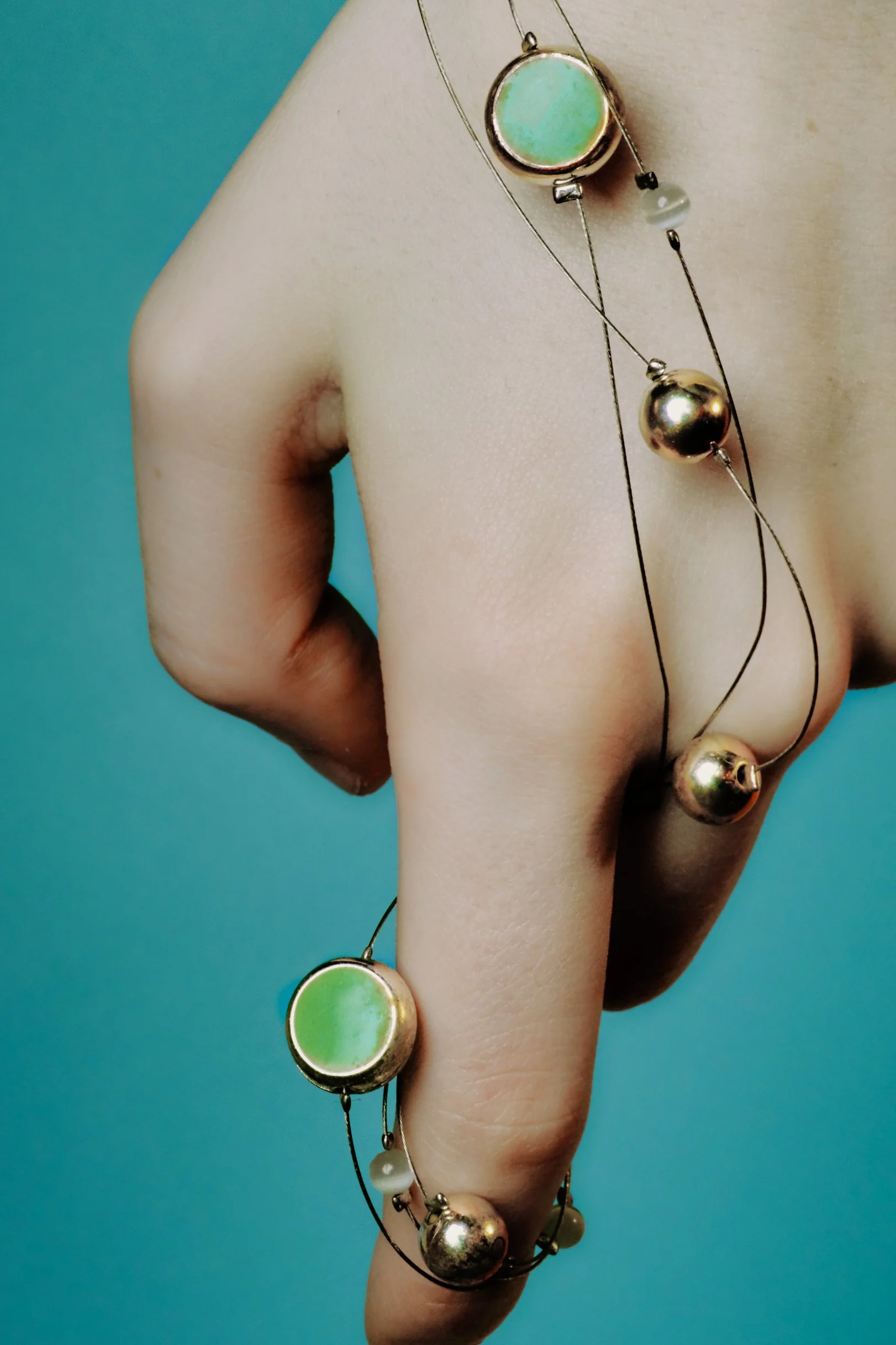 Hands and wrists with bracelet jewelry with a solid aqua background. JSnaps Product E-commerce Commercial Photography New York City 