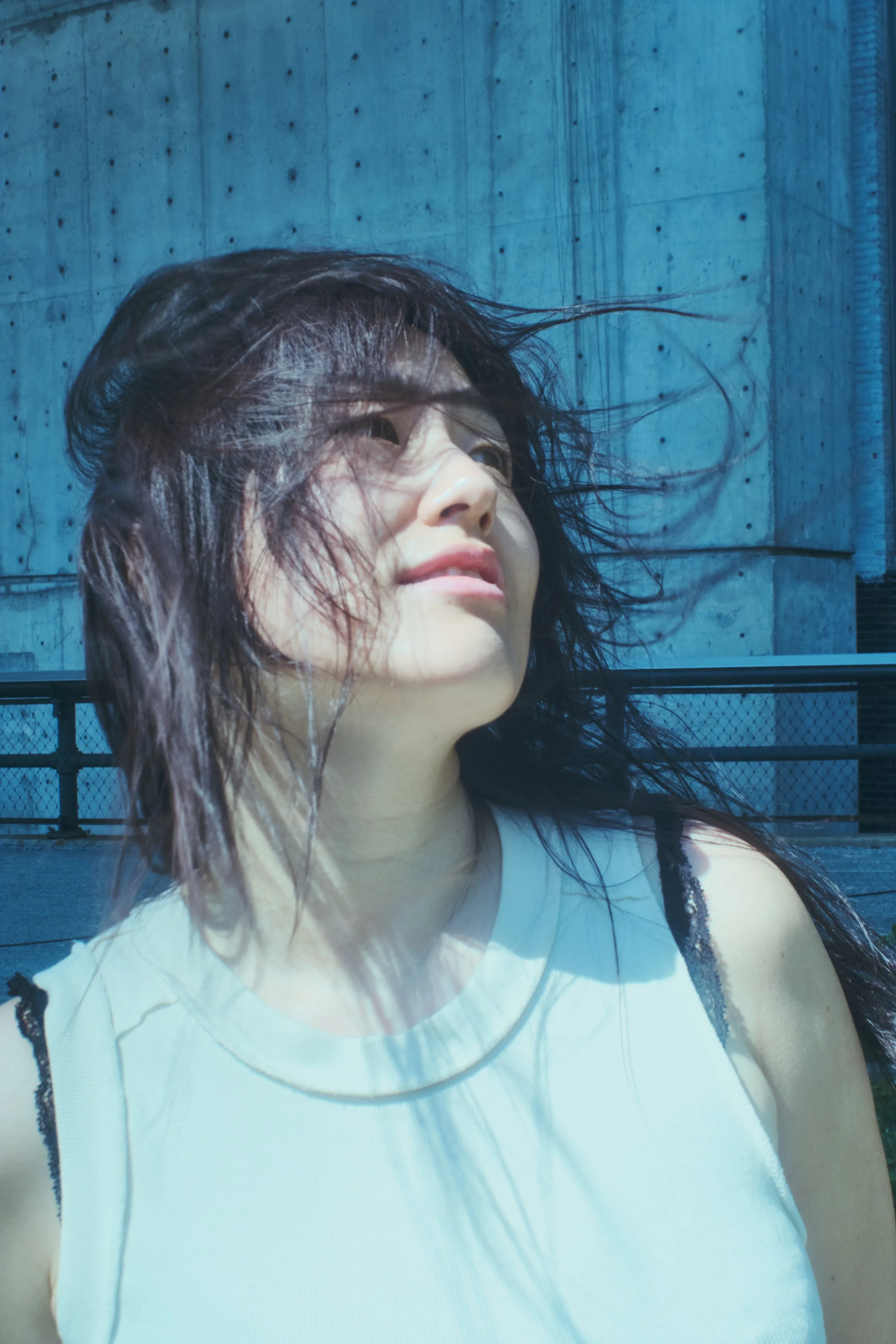 A woman with wet hair looking up in sunlight against a concrete building background. JSnaps Photography New York City Fashion lifestyle photography 