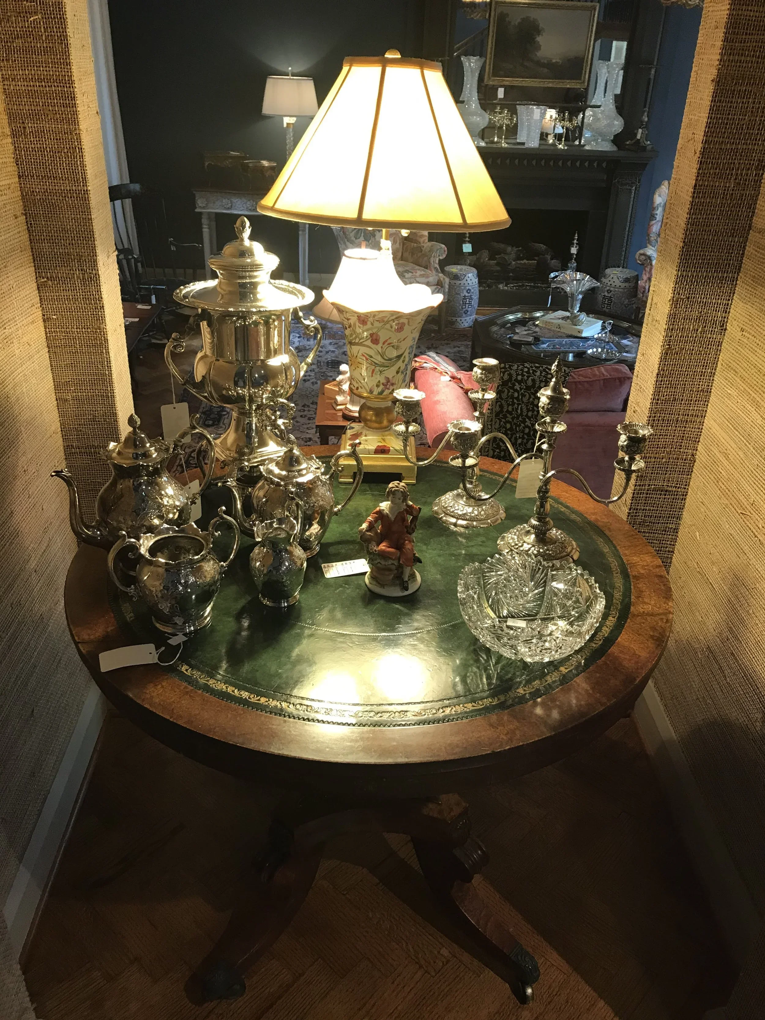 Silver serving pieces and collectibles displayed on an antique table
