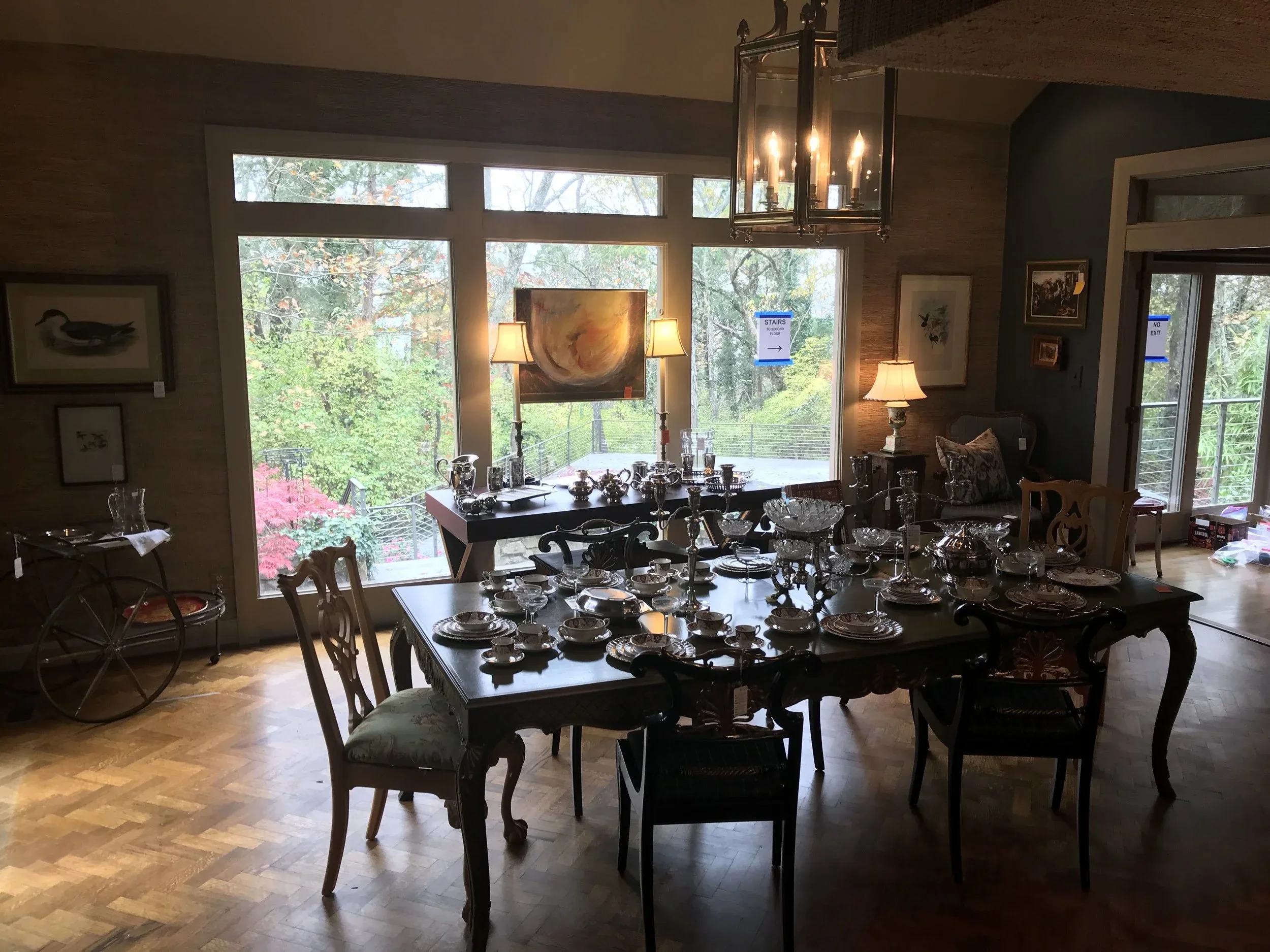 Dining room arranged with fine china, furnishings, and lighting for an estate sale