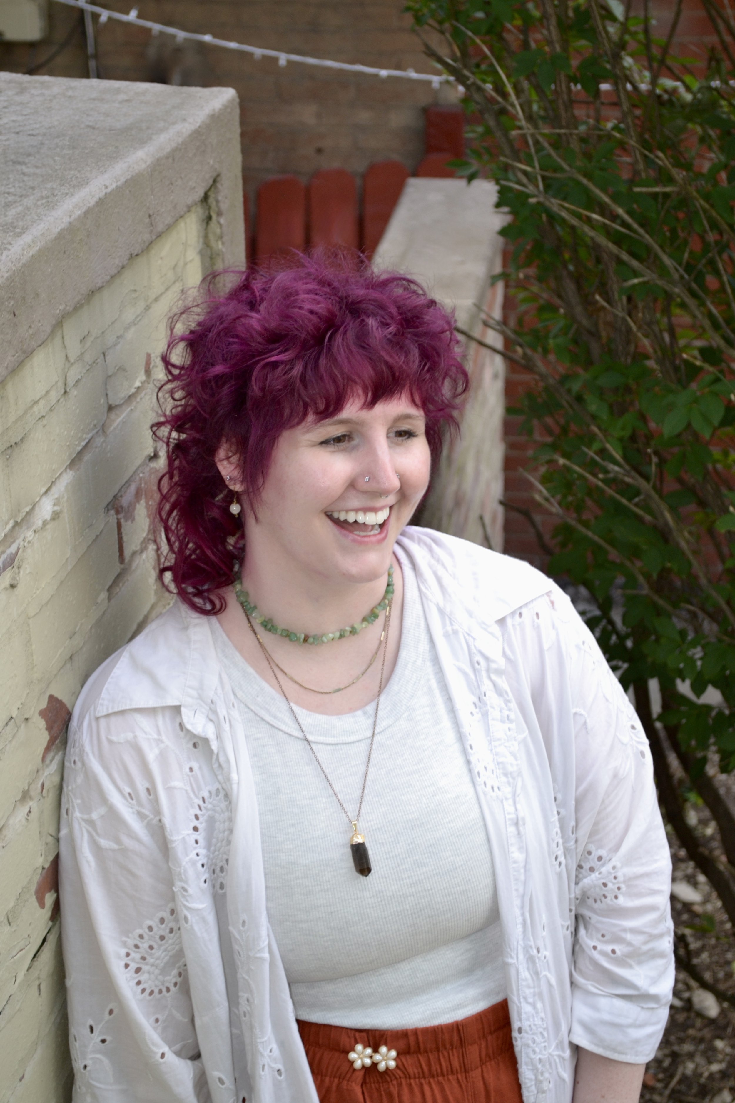 Person with purple hair is looking off toward the right and smiling