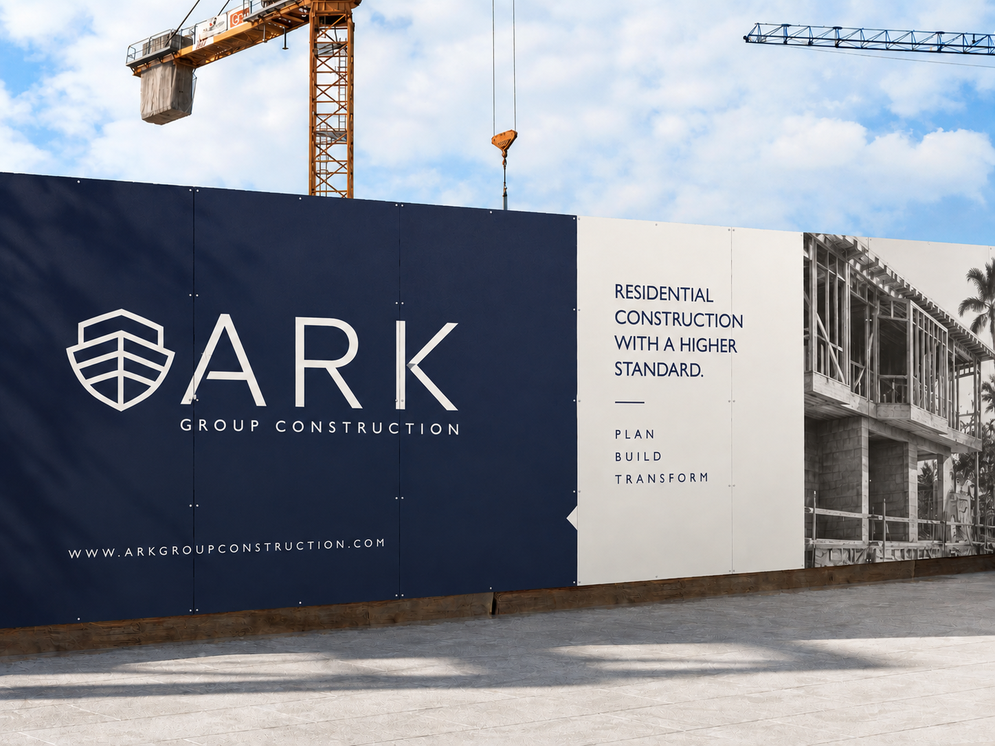 Construction site fence with ARK Group Construction sign, showing a blueprint of a building and a construction crane in the background.