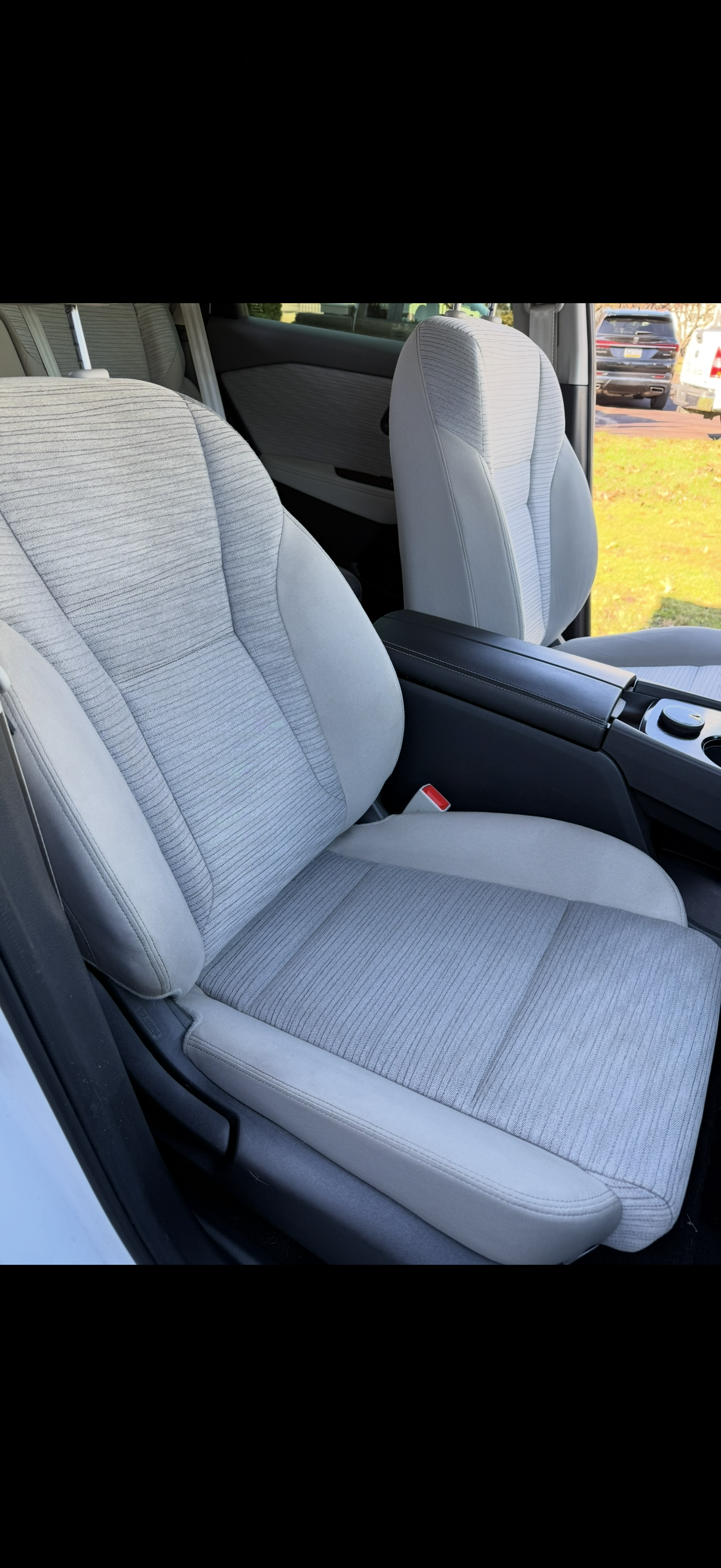 Front passenger seat in a car with light-colored, striped fabric upholstery.