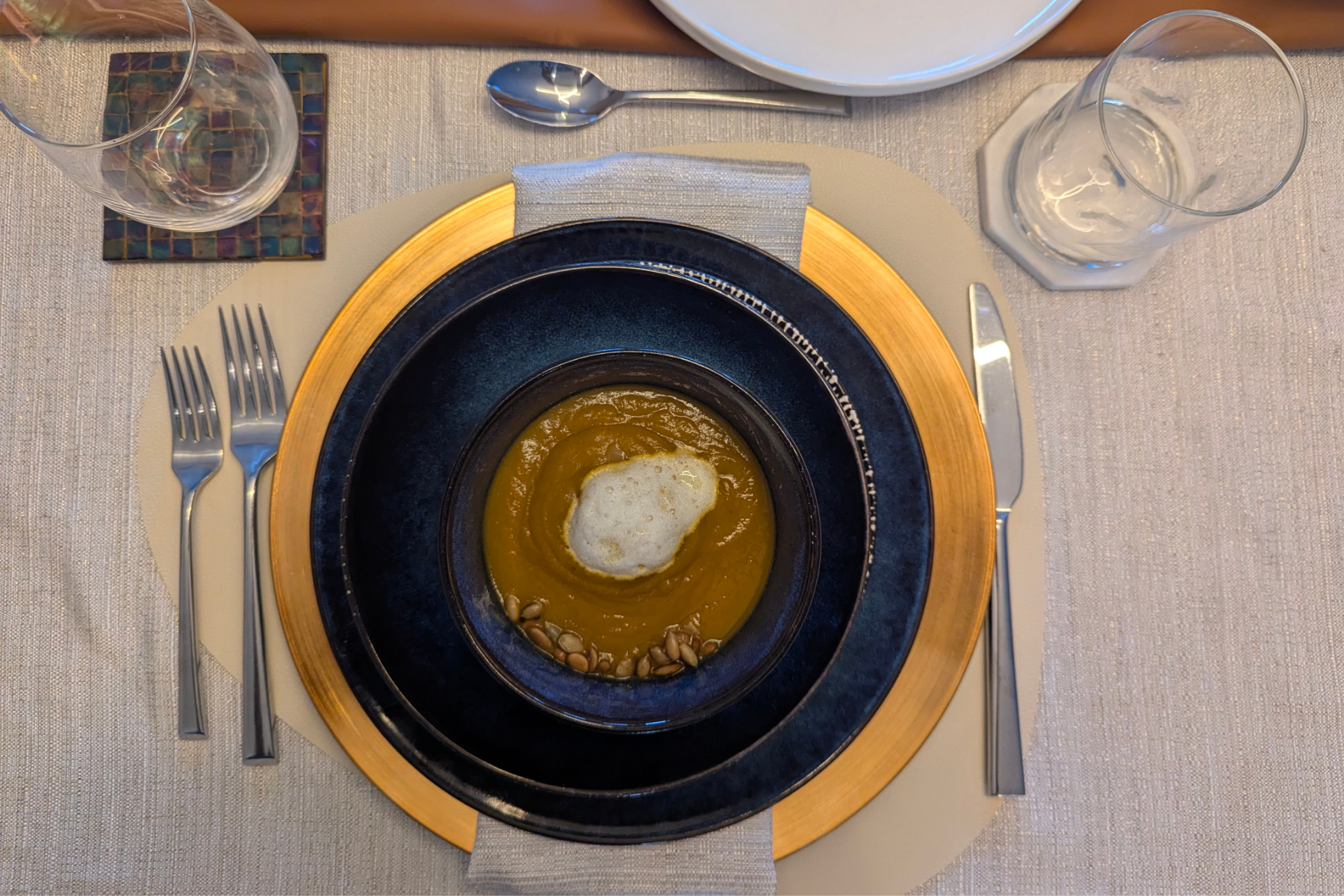table setting with butternut squash soup, milk foam and toasted pumpkin seeds