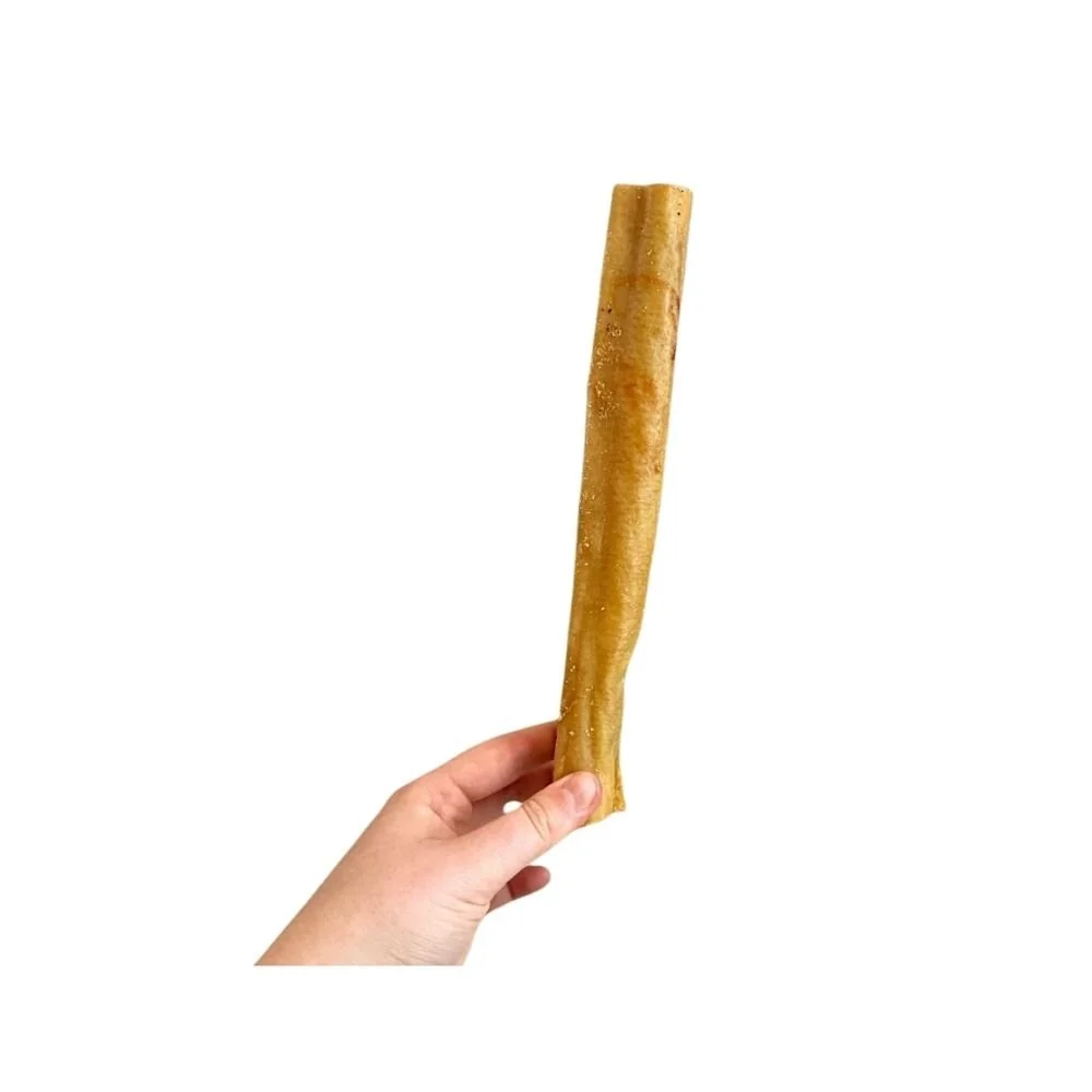 A person holding a single thick Paddock Farm air-dried pork roll chew vertically against a white background.
