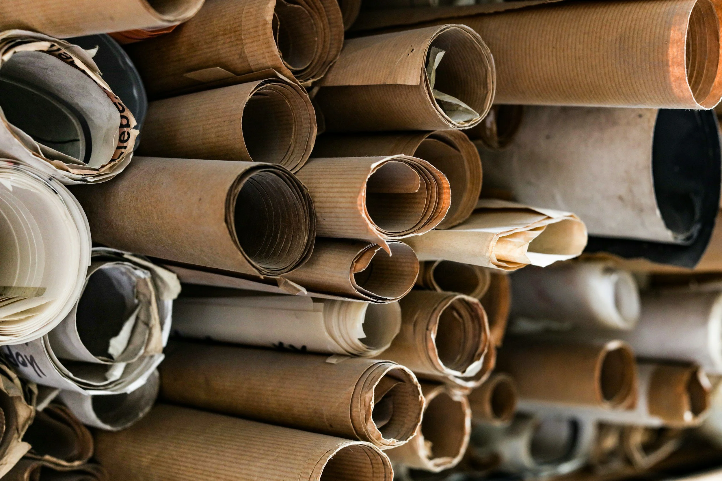 Rows of rolled-up brown and white paper or cardboard in a storage or workshop setting.