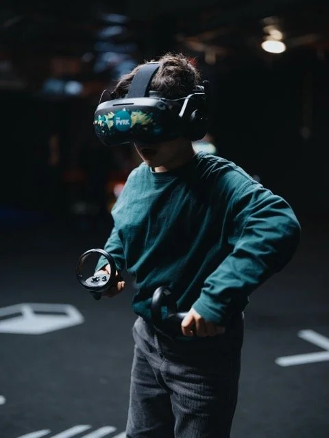 Child wearing a virtual reality headset and holding a controller in a dark environment