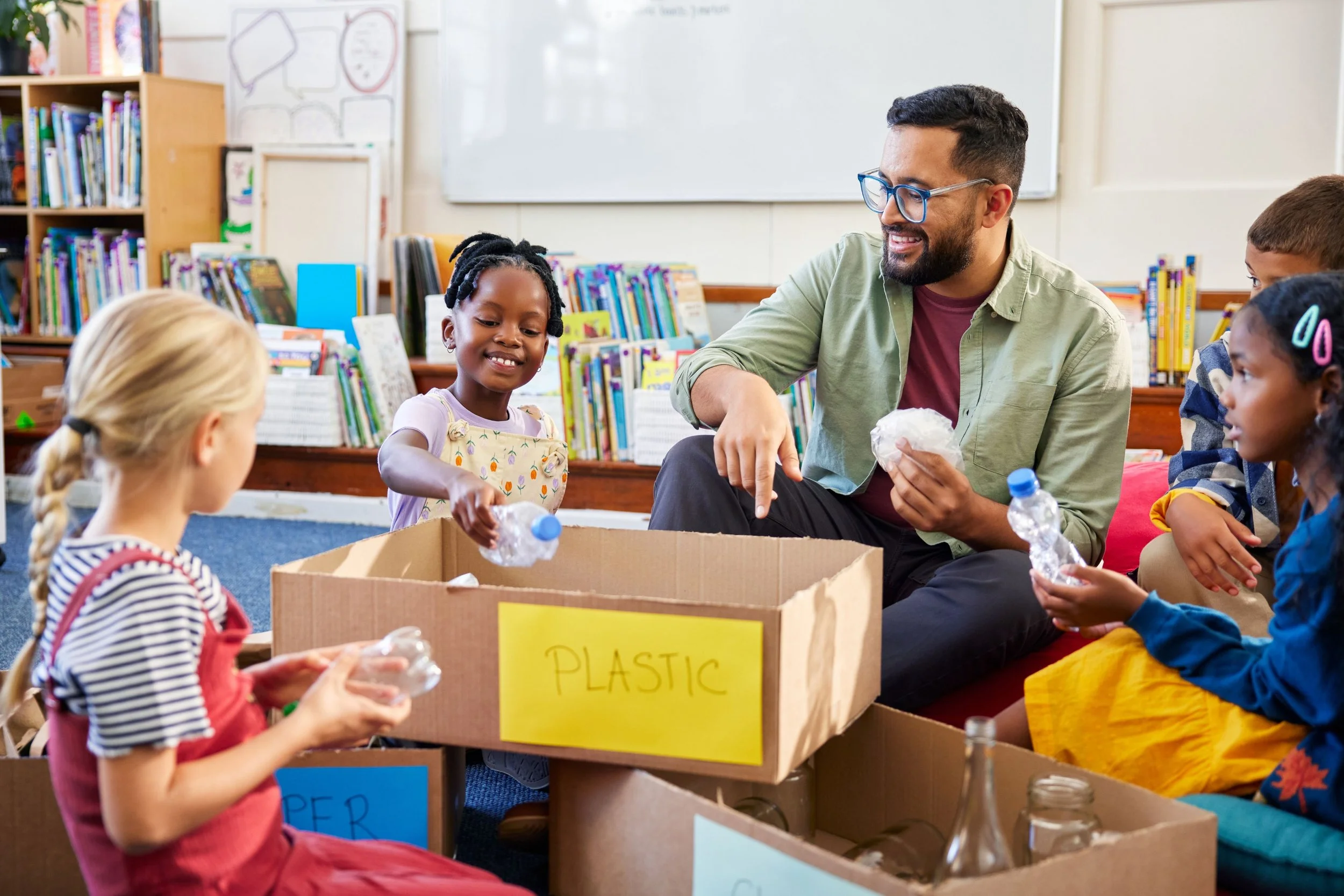 Teacher with students sorting plastic and glass items