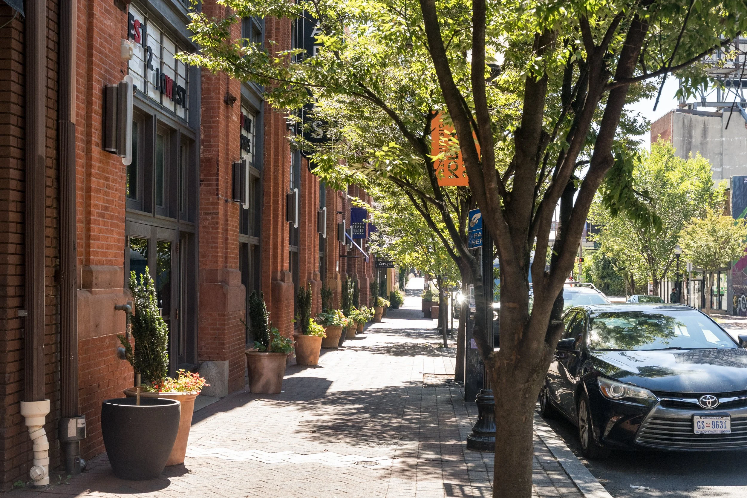 View south on N Charles St. from Theatre Parking toward Amtrak Penn Station, with The Charles Theatre, Tapas Teatro, and Alma Cocina Latina visible along the block.