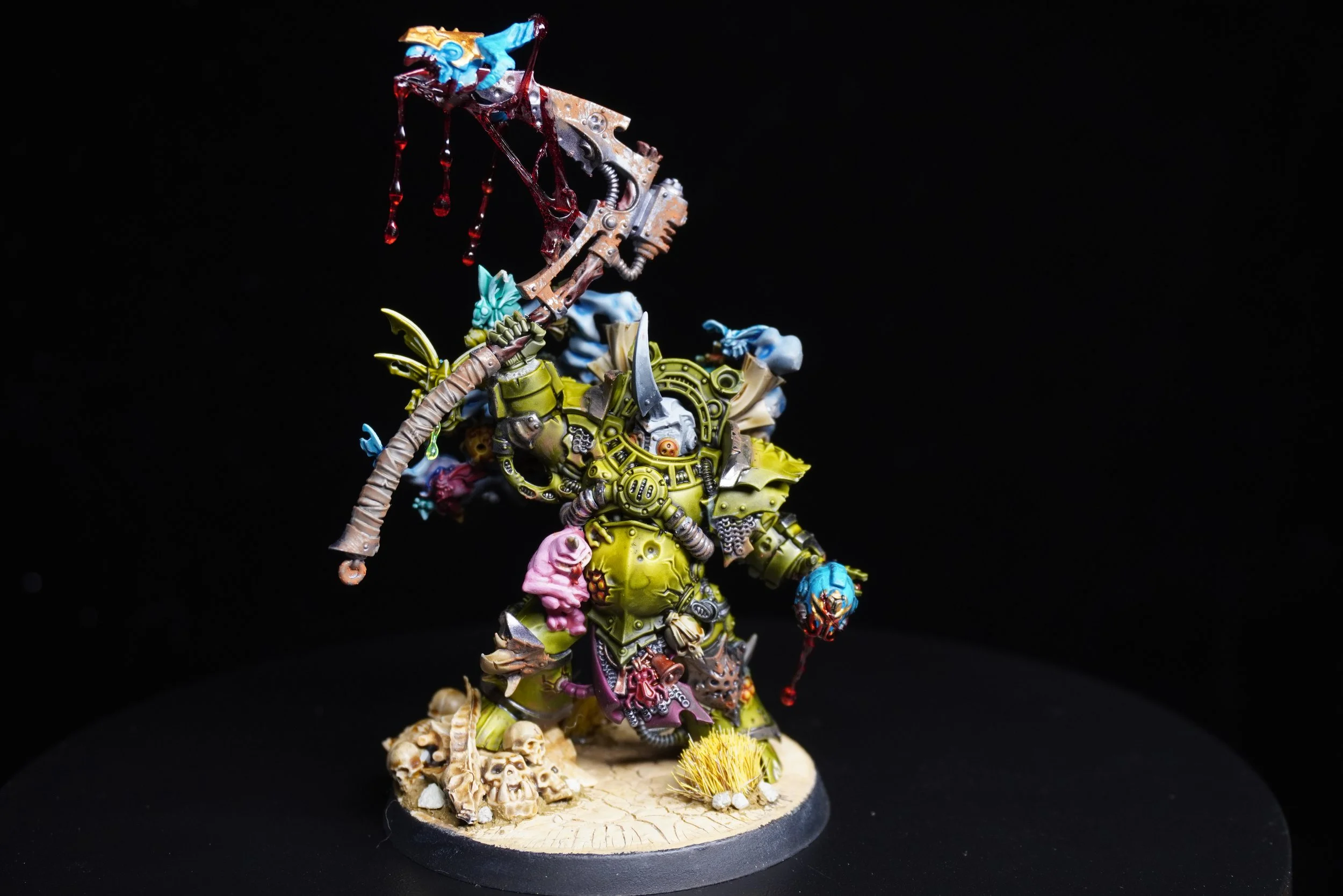 Colorful miniature figure of a fantasy armored warrior holding a weapon, standing on a base decorated with skulls and sand, against a black background.