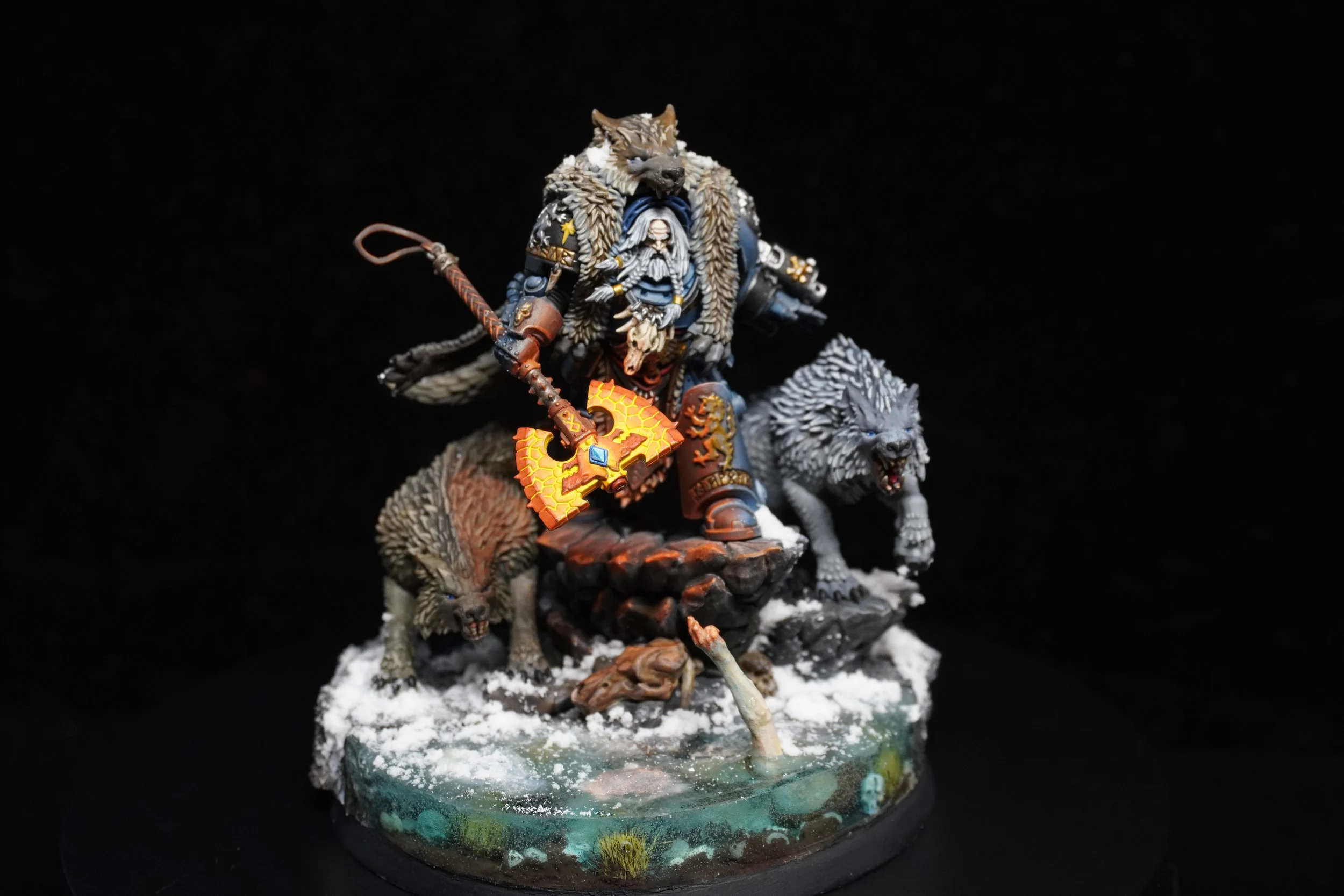 Detailed painted miniature of a fantasy warrior with wolf companions, holding a flaming axe, standing on a snowy base.