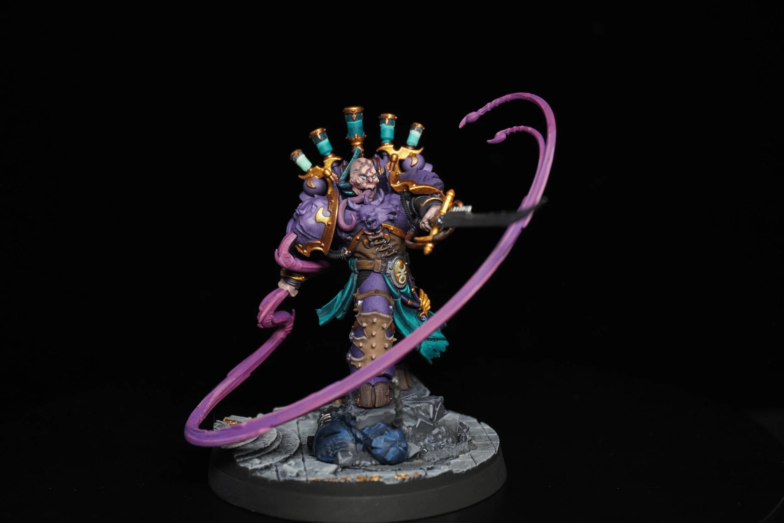 Miniature figure of a fantasy villain with purple skin, dressed in dark robes with gold accents, holding a sword, surrounded by purple tentacles, standing on rocky base.