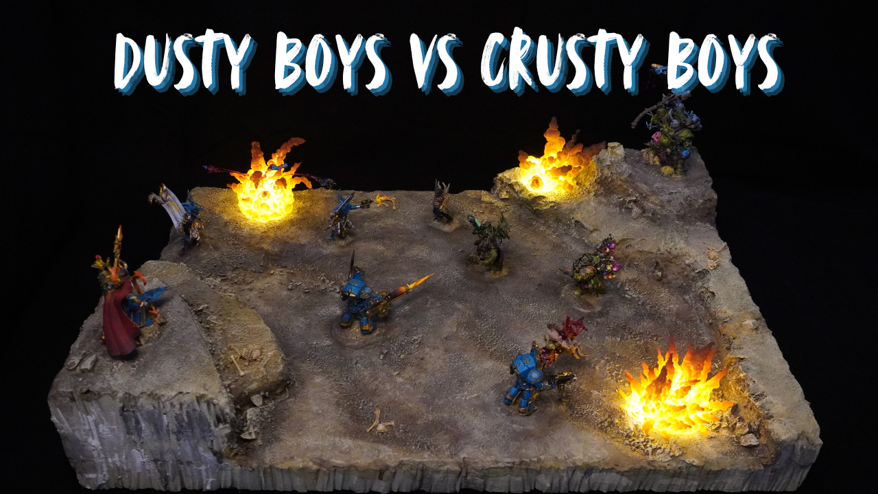 Tabletop miniature diorama of fantasy battle scene with armored warriors and flames, titled 'Dusty Boys vs Crusty Boys'.