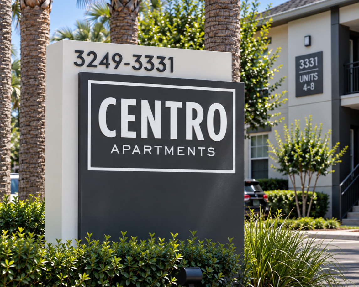 Sign for Centro Apartments with the address 3249-3331, located in front of an apartment complex with palm trees, shrubs, and a walk-up building.