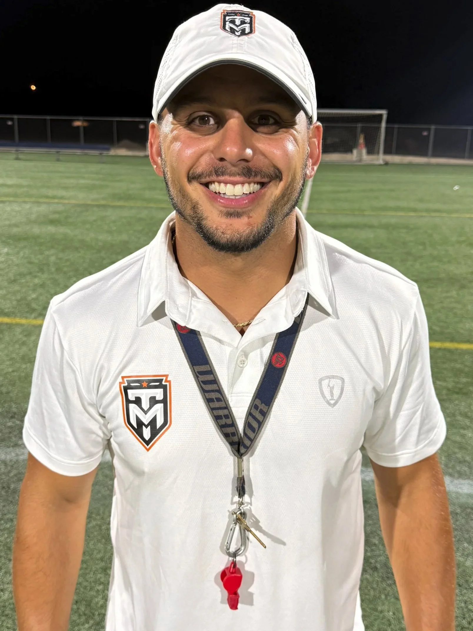 Ed Torriero, director of Texas Made in a white Texas Made polo and hat on a lacrosse field at Night. 