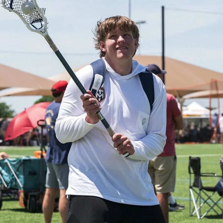 Cole catching a ball in his stick at an outdoor tournament.