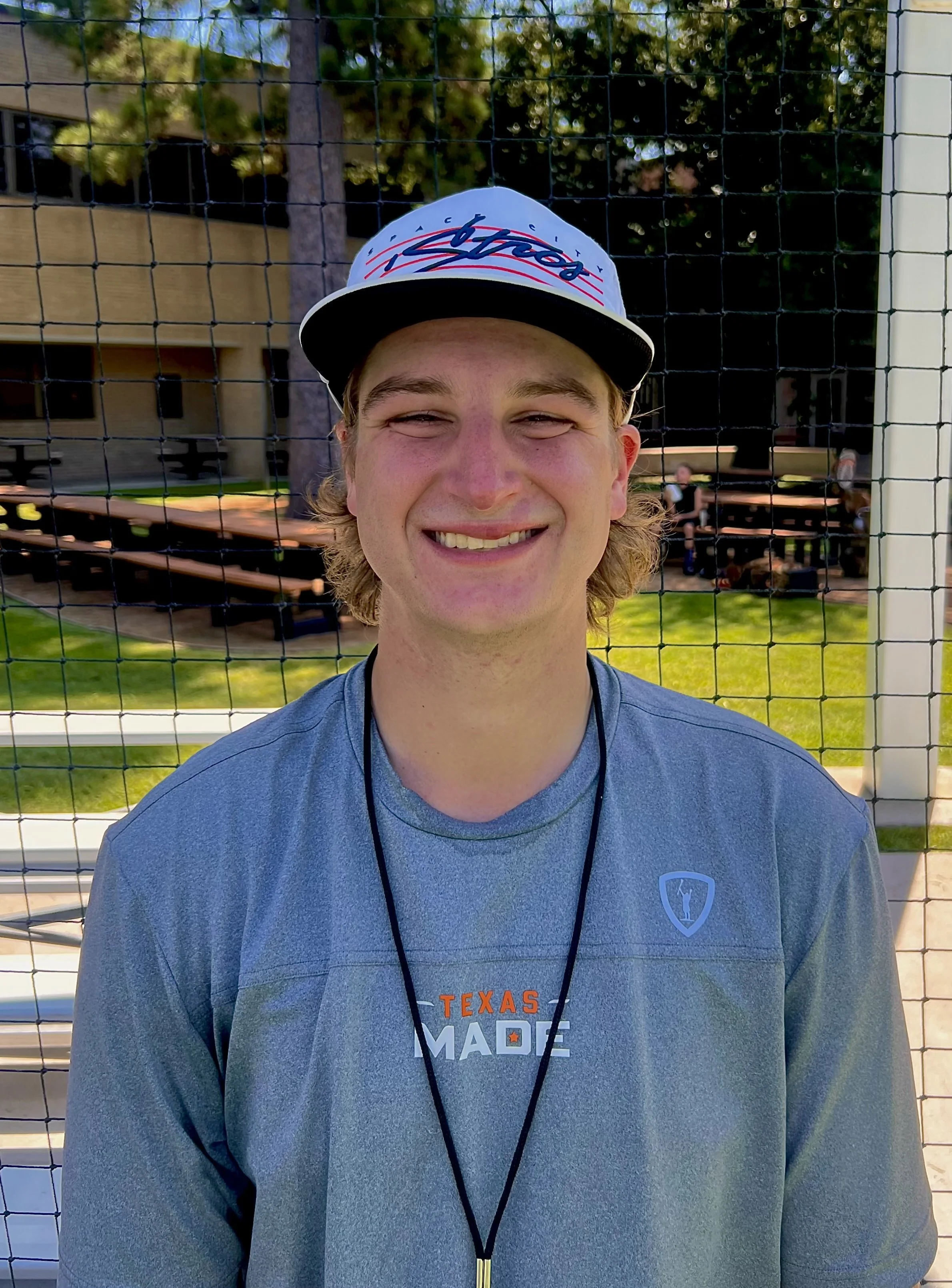 Cooper Leonard smiling in Texas Made lacrosse apparel beside a lacrosse field.
