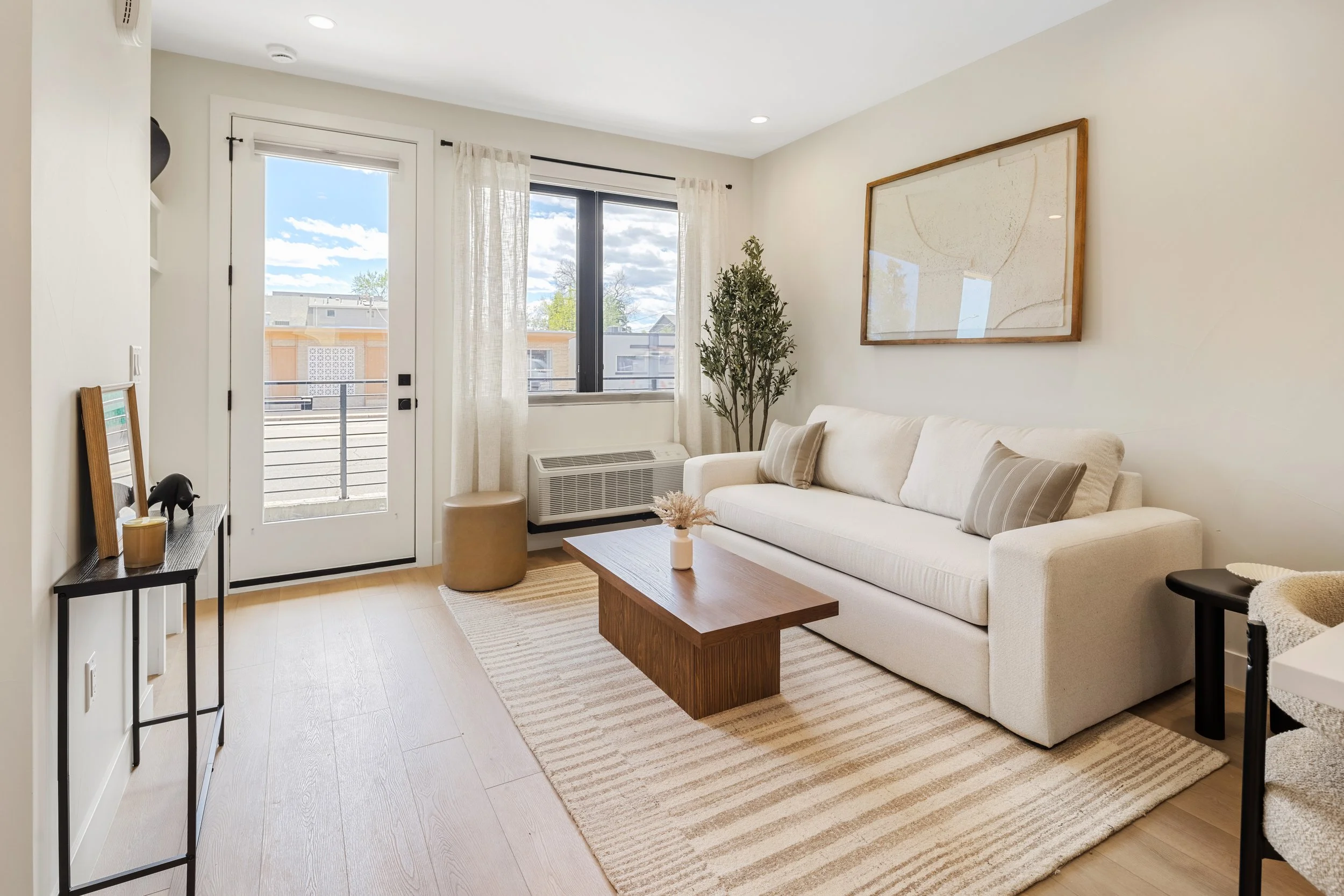Open concept living room and kitchen in 1-bedroom unit at Berkeley Residences Denver, featuring white cabinetry and contemporary finishes
