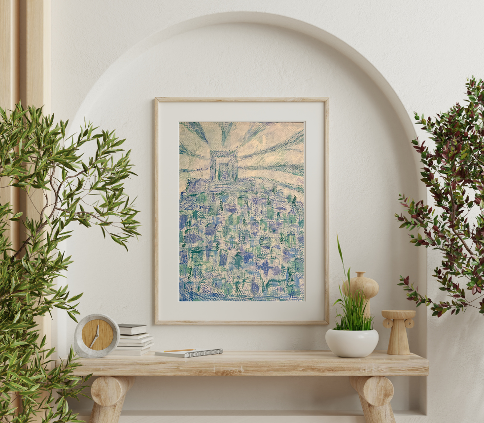 A framed painting of Paris, with the Eiffel Tower in the background and city rooftops below, hanging on a white wall above a wooden table with decorative plants and objects.