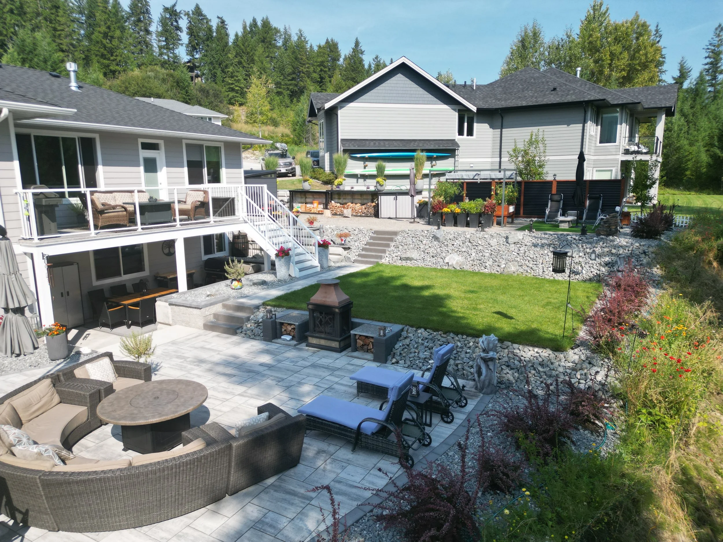 Professional backyard landscaping in Salmon Arm BC with paver patio, retaining walls, decorative rock and modern outdoor living design.
